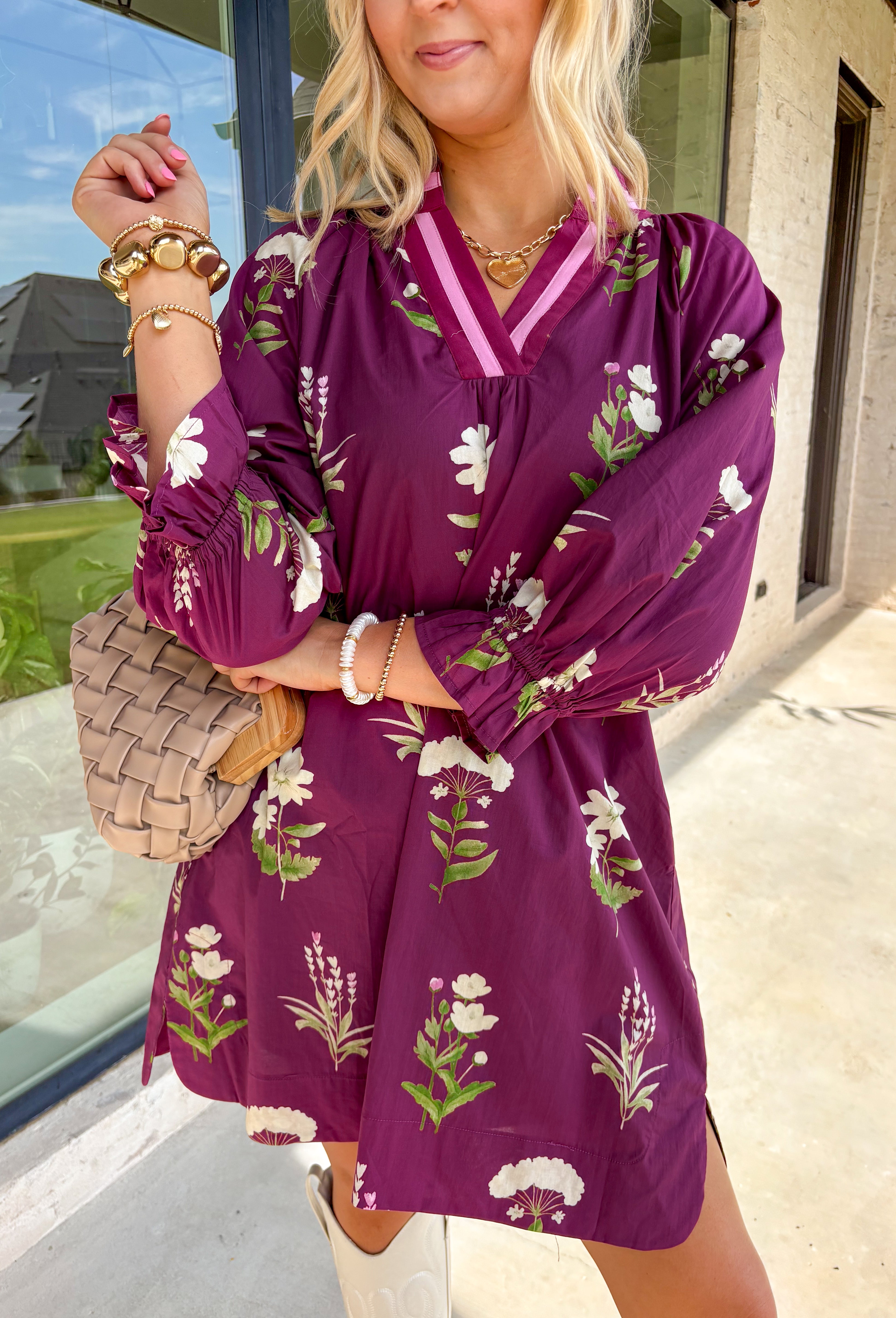 This plum floral dress is giving fall garden party—but make it chic The soft long sleeves are finished with a playful elastic ruffle, while the neutral floral print pops with dreamy shades of cream, pink, and olive. A contrasting trim along the top adds just the right amount of detail. Lined for comfort and style, it’s the kind of dress that goes from pumpkin patch strolls to dinner dates without missing a beat.