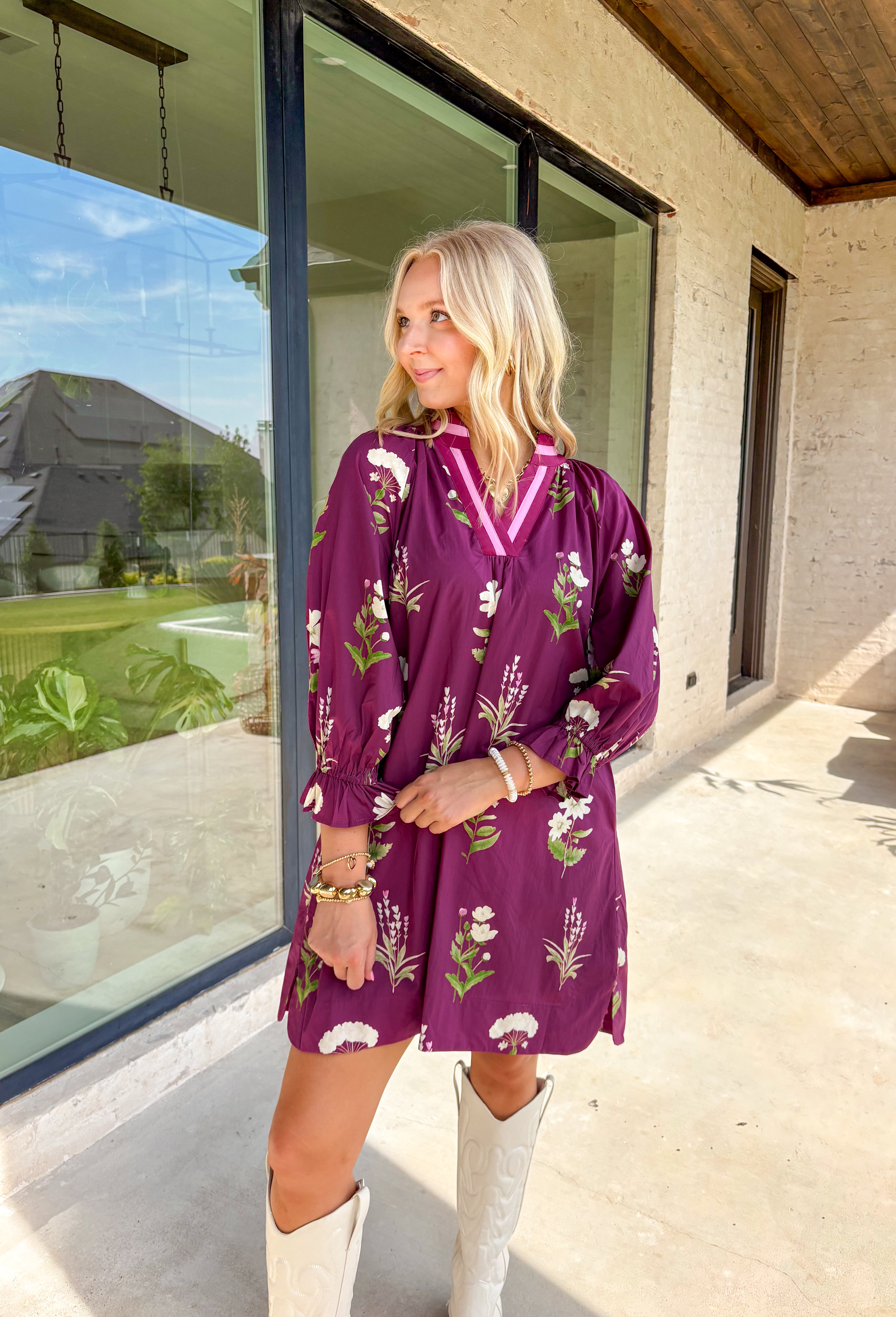 This plum floral dress is giving fall garden party—but make it chic The soft long sleeves are finished with a playful elastic ruffle, while the neutral floral print pops with dreamy shades of cream, pink, and olive. A contrasting trim along the top adds just the right amount of detail. Lined for comfort and style, it’s the kind of dress that goes from pumpkin patch strolls to dinner dates without missing a beat.