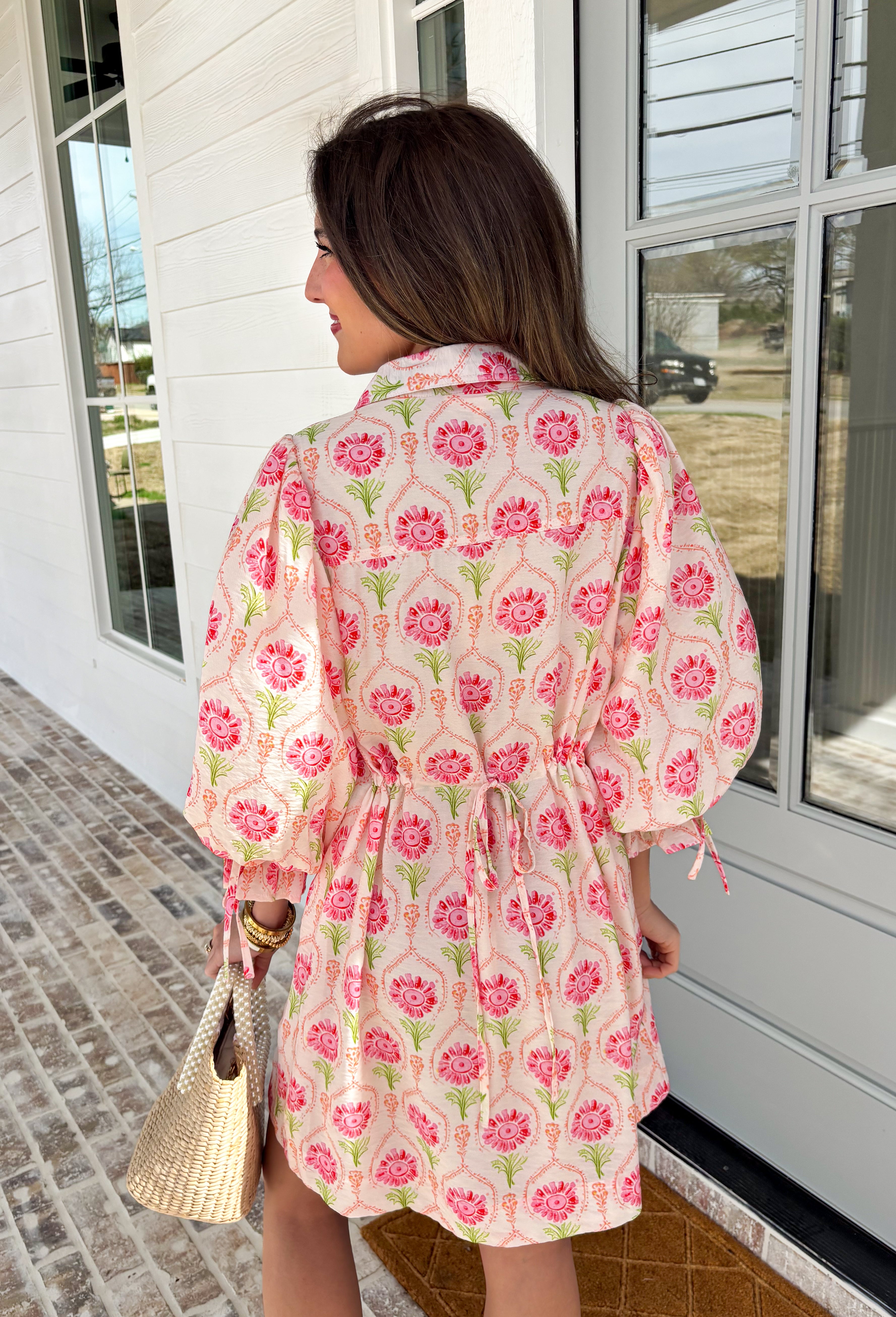Bright, breezy, and full of spring charm, this off-white dress by Entro is an easy favorite for sunny days ahead. Featuring a colorful floral print with pops of pink, coral, and green, it feels cheerful and perfectly seasonal. The collared neckline adds a classic touch, while the ¾ length sleeves with elastic cuffs and adjustable tie details give it a relaxed, feminine finish. Fully lined for comfortable wear, this dress is effortlessly polished and ready for everything from brunch dates to spring events.