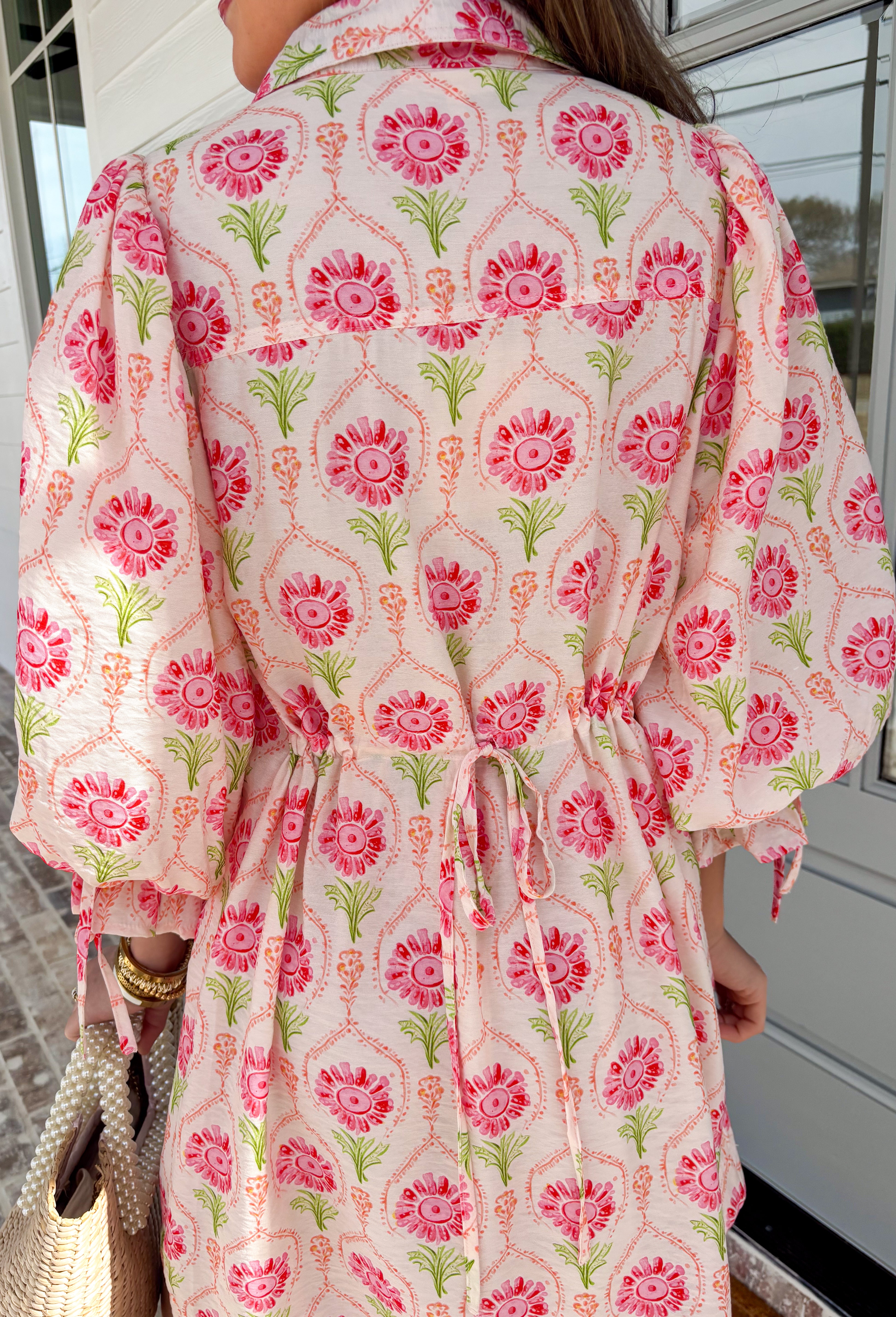 Bright, breezy, and full of spring charm, this off-white dress by Entro is an easy favorite for sunny days ahead. Featuring a colorful floral print with pops of pink, coral, and green, it feels cheerful and perfectly seasonal. The collared neckline adds a classic touch, while the ¾ length sleeves with elastic cuffs and adjustable tie details give it a relaxed, feminine finish. Fully lined for comfortable wear, this dress is effortlessly polished and ready for everything from brunch dates to spring events.