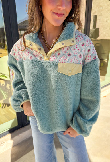 Cozy meets fresh in this sage sherpa pullover by New In — the perfect layer for cool spring mornings and breezy evenings. Designed with a soft sherpa body, this pullover features a floral quilted print along the top for a sweet seasonal touch. Pale yellow trim at the quarter button closure and a matching front pocket add a cheerful pop of color, making this piece feel bright, playful, and easy to wear as the seasons change.