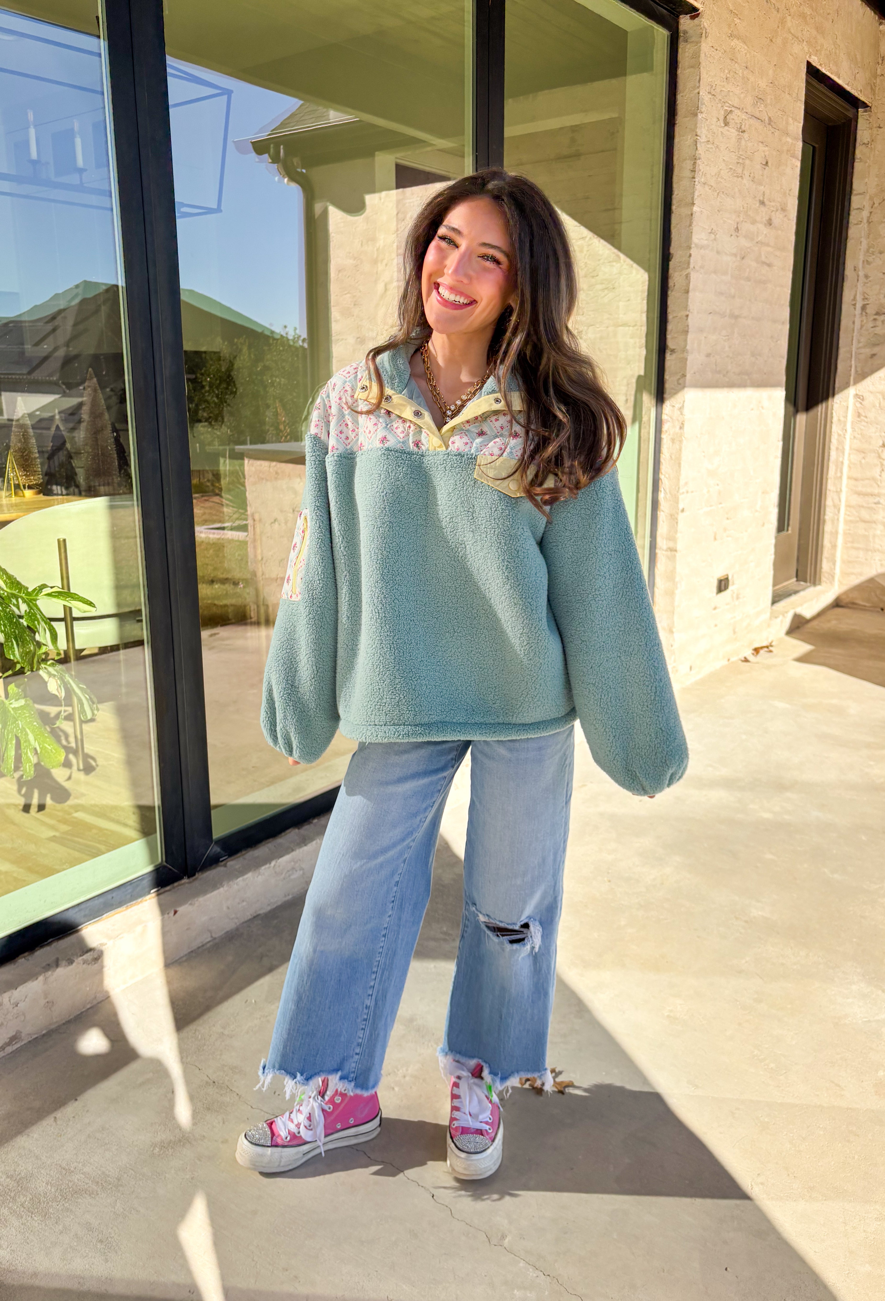 Cozy meets fresh in this sage sherpa pullover by New In — the perfect layer for cool spring mornings and breezy evenings. Designed with a soft sherpa body, this pullover features a floral quilted print along the top for a sweet seasonal touch. Pale yellow trim at the quarter button closure and a matching front pocket add a cheerful pop of color, making this piece feel bright, playful, and easy to wear as the seasons change.