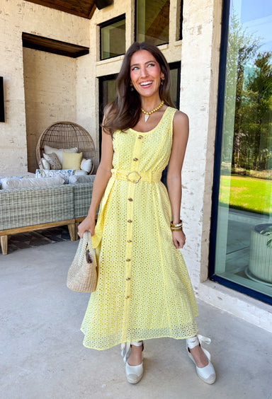 Bold, polished, and beautifully detailed — this lemon yellow eyelet lace midi dress is a true standout. The intricate eyelet lace gives it texture and dimension, while the gold textured button-down front adds a hint of shine that elevates the entire look. Designed with a matching belt featuring a gold buckle, this dress cinches the waist for a flattering, feminine silhouette. Smocking along the back provides comfortable stretch, and the back zipper closure keeps the fit secure and streamlined. 