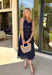 Bold, polished, and beautifully detailed — this navy eyelet lace midi dress is a true standout. The intricate eyelet lace gives it texture and dimension, while the gold textured button-down front adds a hint of shine that elevates the entire look. Designed with a matching belt featuring a gold buckle, this dress cinches the waist for a flattering, feminine silhouette. Smocking along the back provides comfortable stretch, and the back zipper closure keeps the fit secure and streamlined.