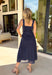 Bold, polished, and beautifully detailed — this navy eyelet lace midi dress is a true standout. The intricate eyelet lace gives it texture and dimension, while the gold textured button-down front adds a hint of shine that elevates the entire look. Designed with a matching belt featuring a gold buckle, this dress cinches the waist for a flattering, feminine silhouette. Smocking along the back provides comfortable stretch, and the back zipper closure keeps the fit secure and streamlined.