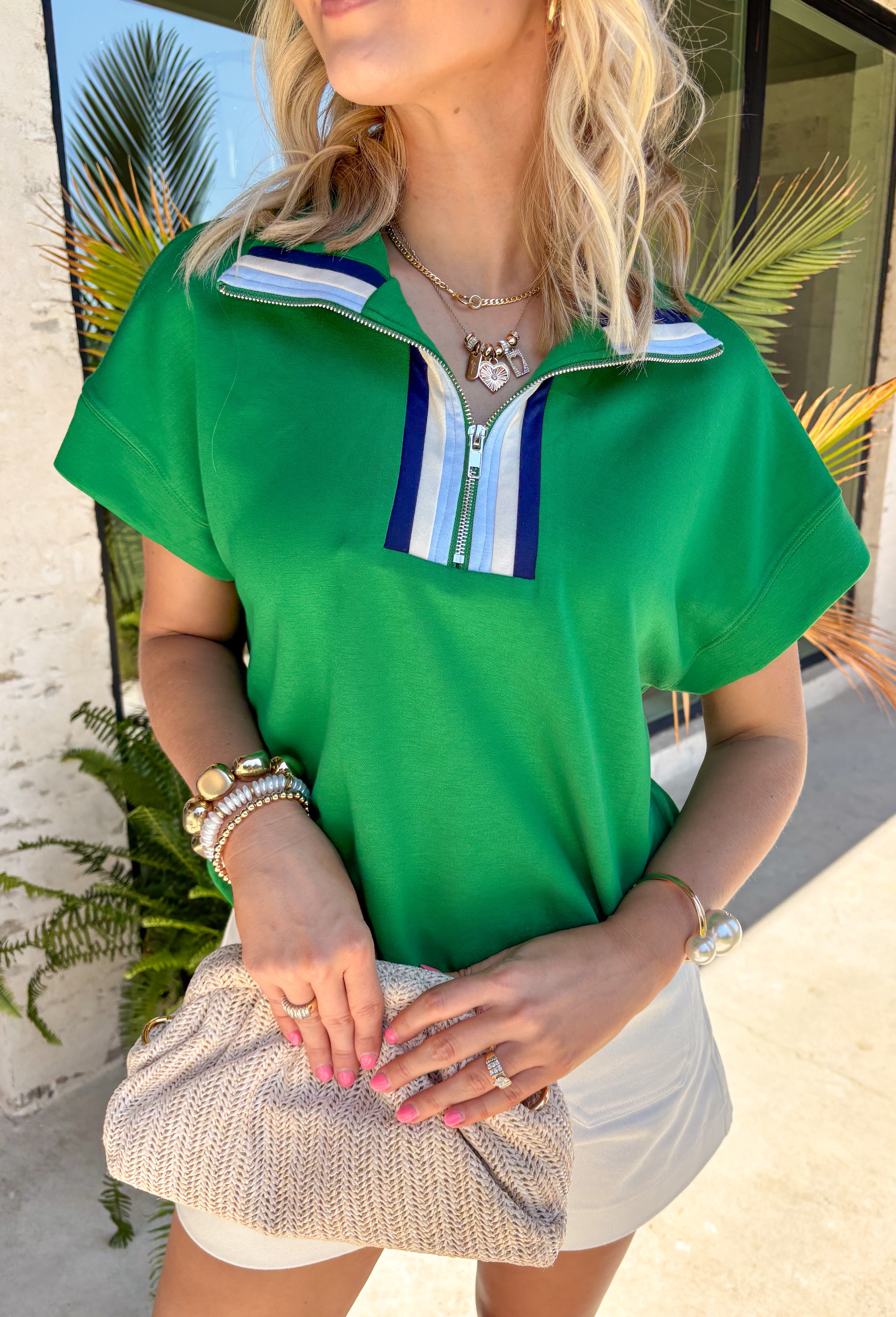 Fresh, sporty, and effortlessly polished, this green zip-front pullover by Umgee is the perfect lightweight layer for spring days. The crisp contrast accents of cream, navy, and light blue add a clean pop, while the zip-front detail gives you adjustable styling—wear it zipped up for a sleek look or slightly open for a more relaxed vibe. You'll find yourself reaching for this top all season long!