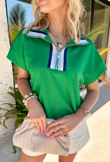 Fresh, sporty, and effortlessly polished, this green zip-front pullover by Umgee is the perfect lightweight layer for spring days. The crisp contrast accents of cream, navy, and light blue add a clean pop, while the zip-front detail gives you adjustable styling—wear it zipped up for a sleek look or slightly open for a more relaxed vibe. You'll find yourself reaching for this top all season long!