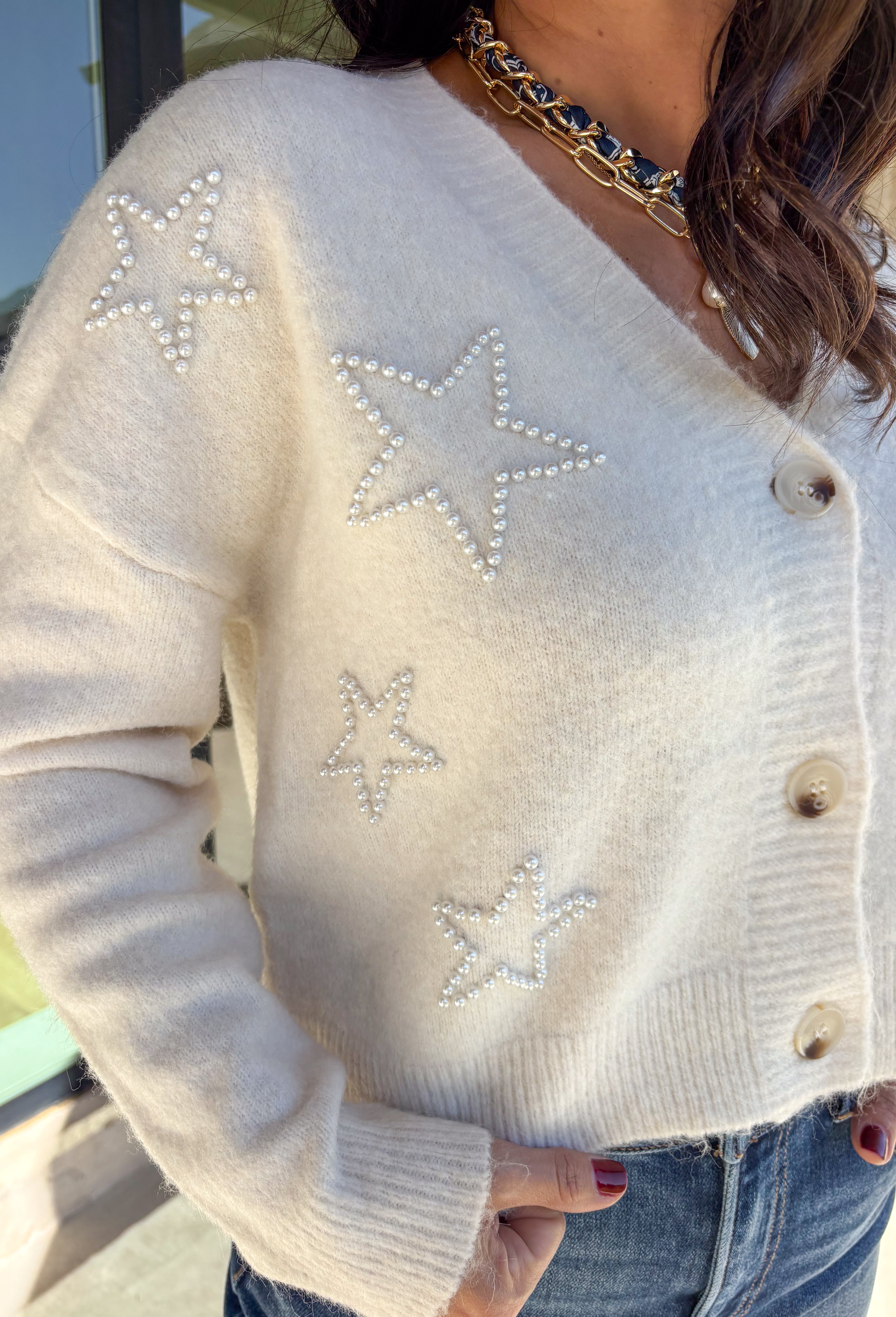 Shine bright this season in this off-white button-down cardigan by Debut. Crafted from a soft, cozy knit, this sweater features delicate pearl star embellishments that add the perfect hint of glam. With its relaxed fit and timeless charm, it’s a dreamy layer for holiday gatherings or casual winter days.
