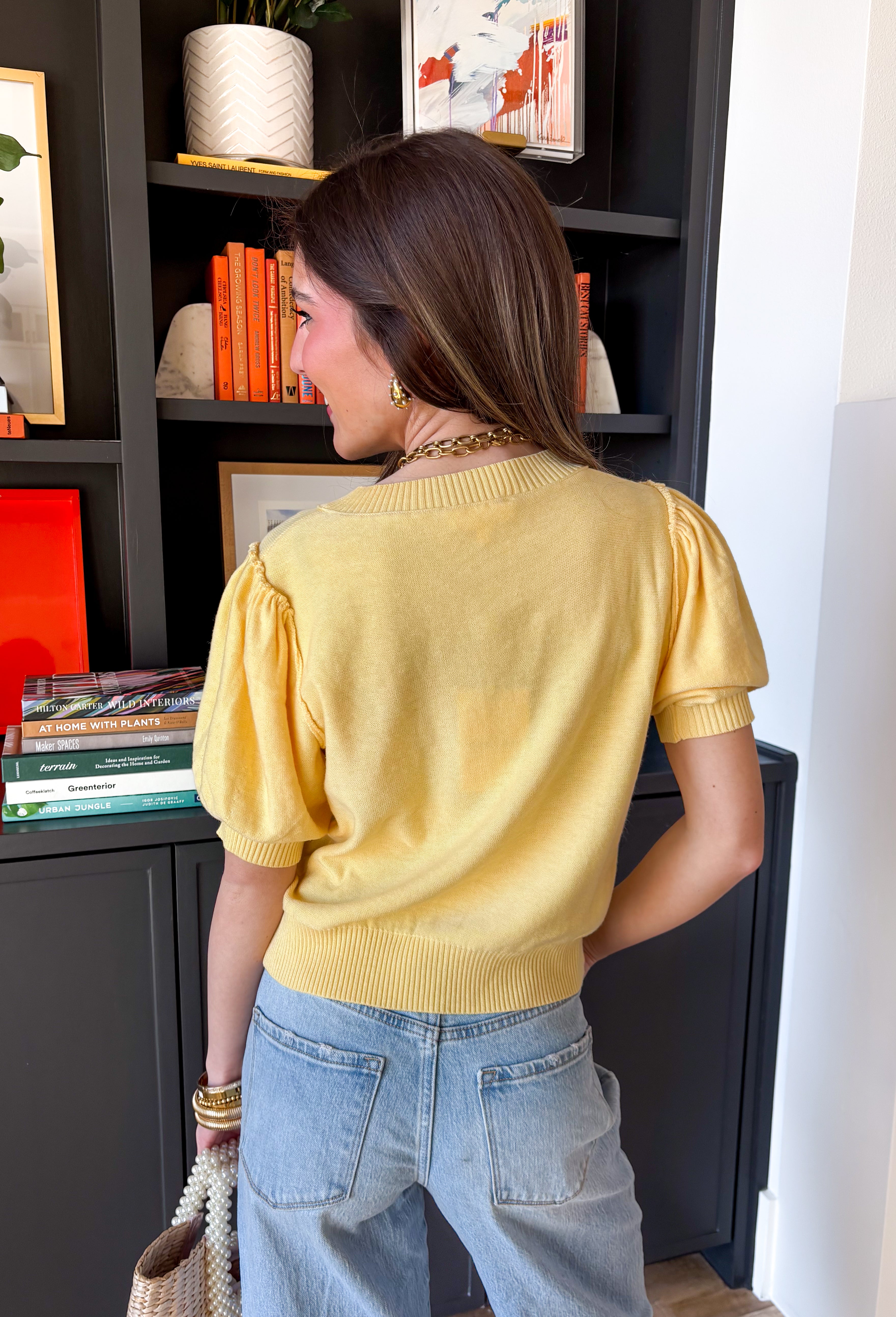 Soft, sunny, and perfect for spring layering, this butter yellow button-down knit top by Entro brings a warm pop of color to your everyday wardrobe. The lightweight knit feels cozy without being heavy, making it ideal for those in-between spring days. Ribbed detailing along the neckline, cuffs, and hem adds subtle texture and a polished finish, while the button-down design makes it easy to wear on its own or layered over a tank.