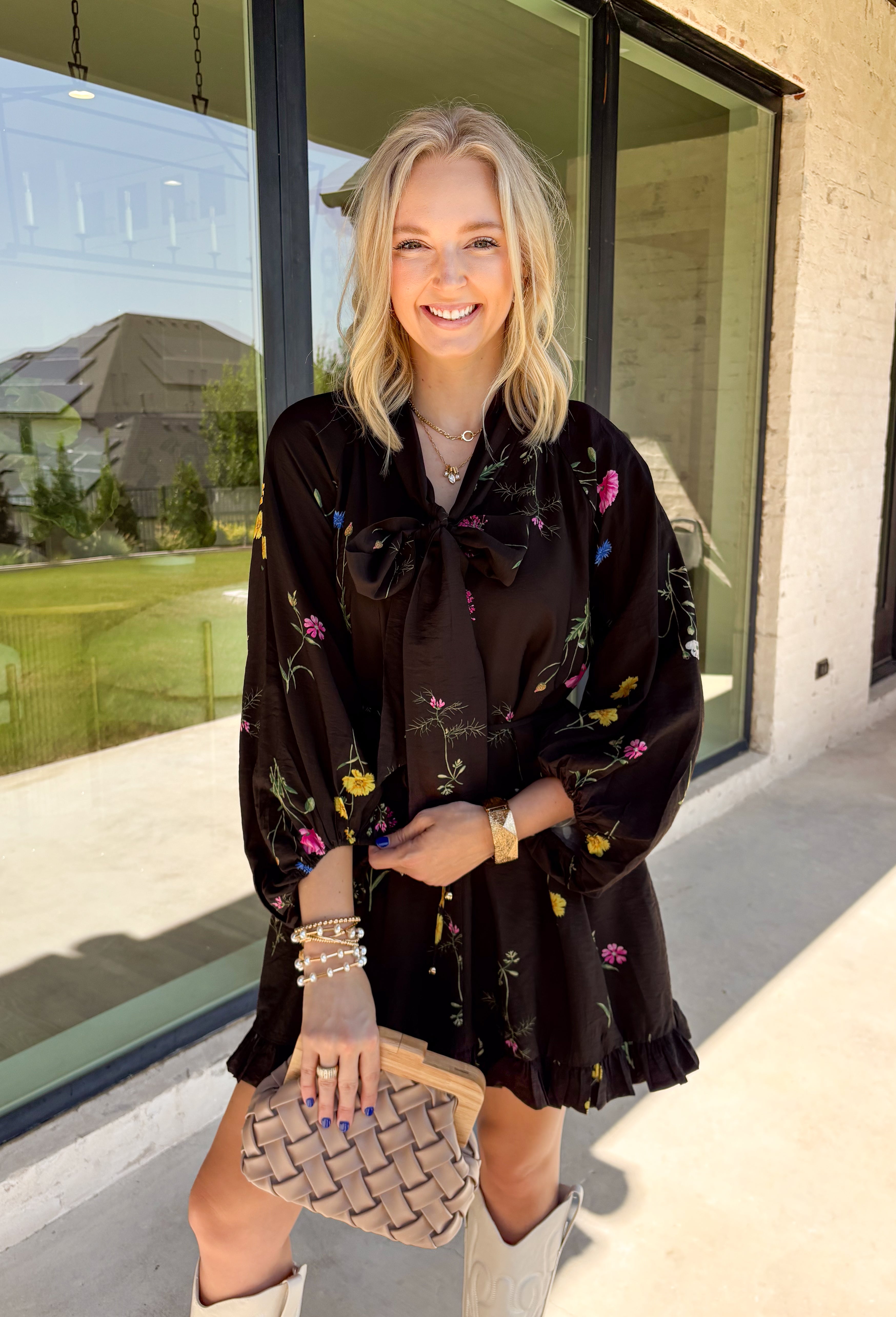 Feminine, chic, and full of seasonal charm, this floral dress is the perfect piece for all your favorite fall occasions. Featuring a classic black backdrop with a vibrant colorful floral print, this dress offers a timeless silhouette with eye-catching details. The flattering v-neckline is accented by a beautiful scarf tie that adds a polished, sophisticated touch, while the self-tie waist creates a customizable fit you'll love. 