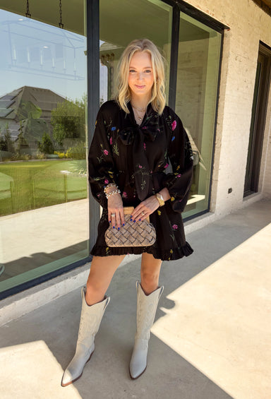 Feminine, chic, and full of seasonal charm, this floral dress is the perfect piece for all your favorite fall occasions. Featuring a classic black backdrop with a vibrant colorful floral print, this dress offers a timeless silhouette with eye-catching details. The flattering v-neckline is accented by a beautiful scarf tie that adds a polished, sophisticated touch, while the self-tie waist creates a customizable fit you'll love. 