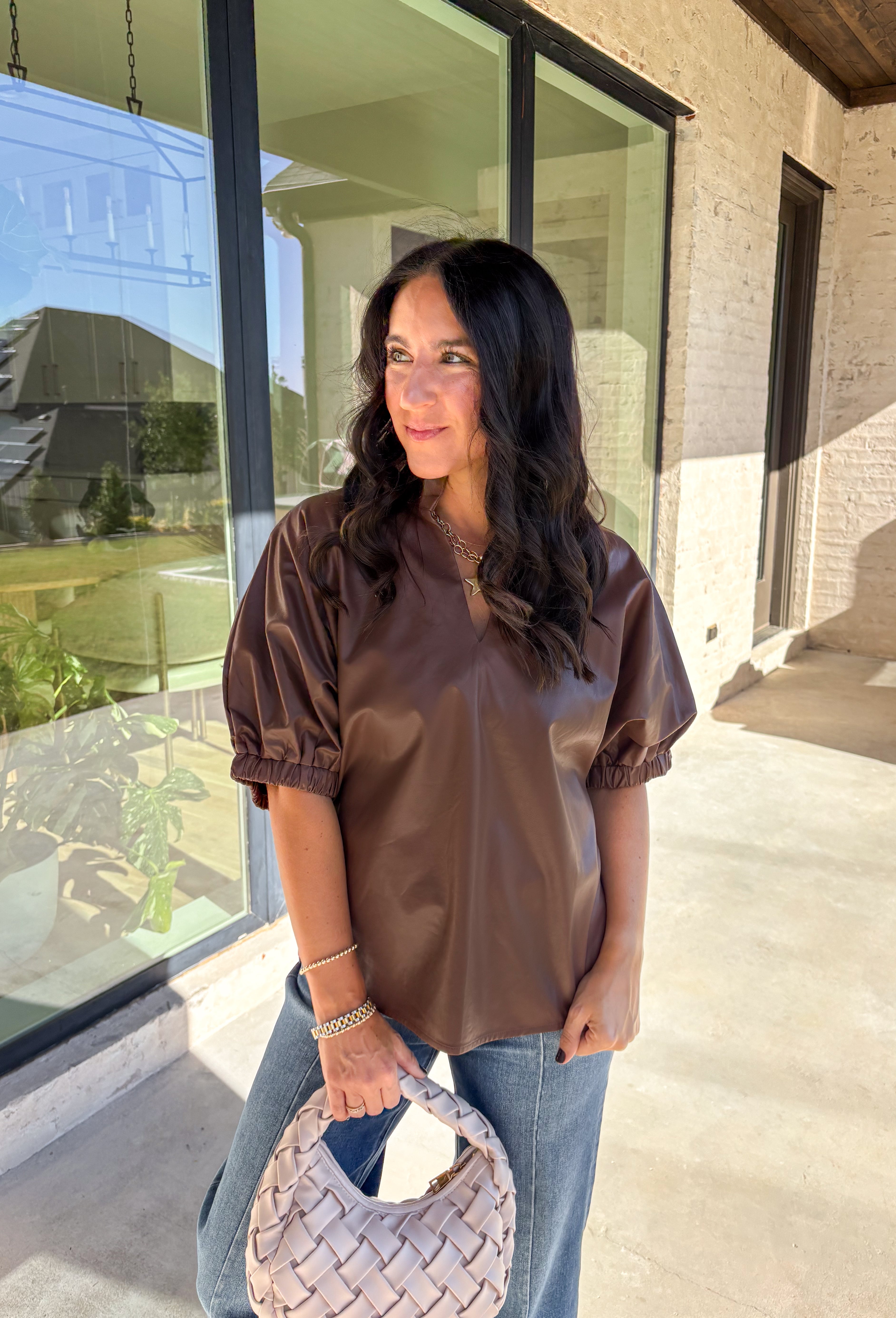 Elevate your wardrobe with this chic brown faux leather top by Entro. Designed with short puff sleeves and elasticated openings, it strikes the perfect balance of structured and feminine. The split v-neckline with a stand collar adds a modern edge, while the soft faux leather finish brings a touch of texture that feels fresh for the season. Perfect for dressing up denim or pairing with skirts, this top is a statement piece you’ll reach for again and again.