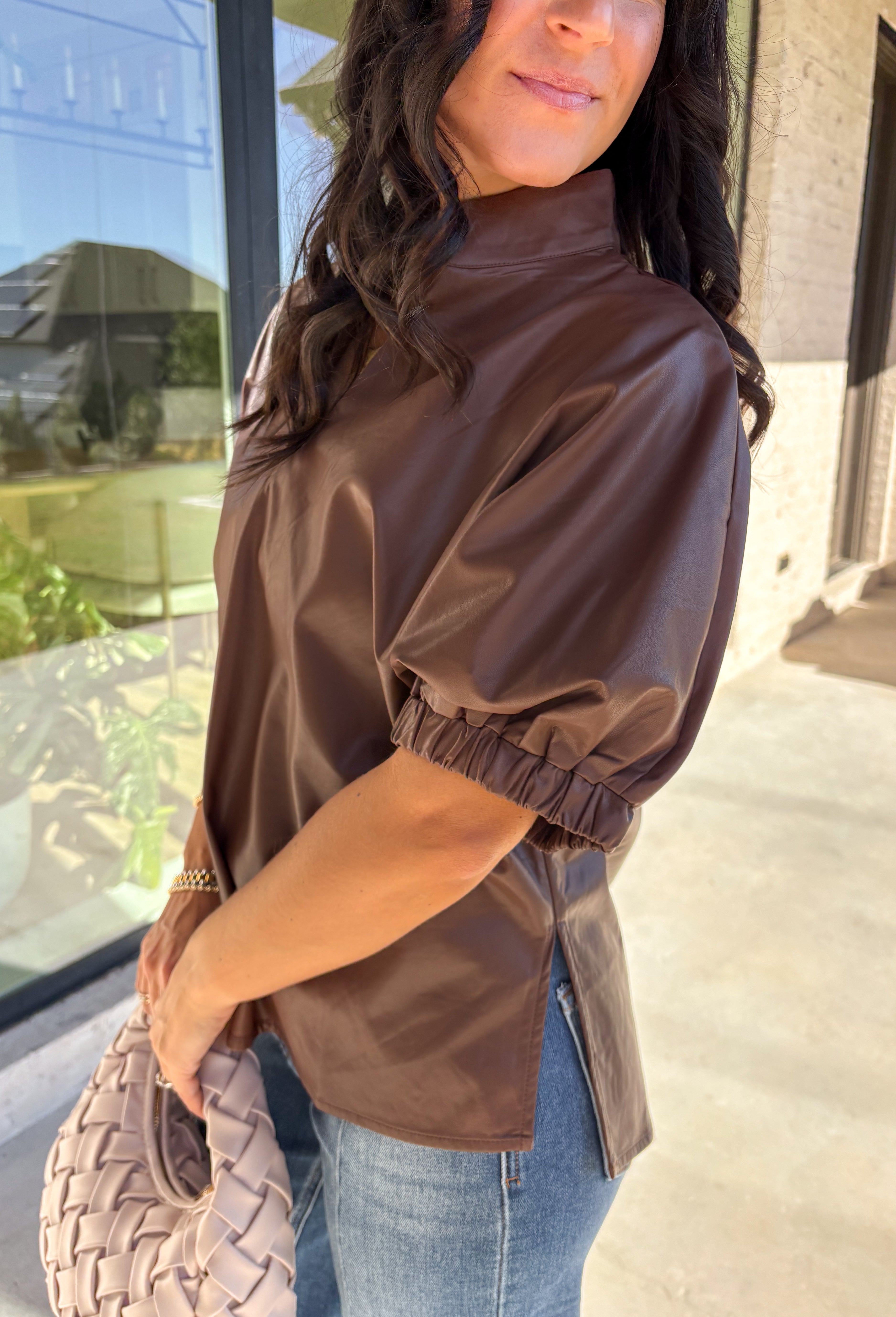 Elevate your wardrobe with this chic brown faux leather top by Entro. Designed with short puff sleeves and elasticated openings, it strikes the perfect balance of structured and feminine. The split v-neckline with a stand collar adds a modern edge, while the soft faux leather finish brings a touch of texture that feels fresh for the season. Perfect for dressing up denim or pairing with skirts, this top is a statement piece you’ll reach for again and again.