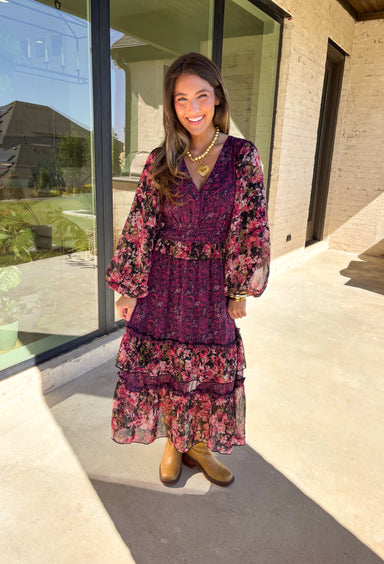 Romantic and striking, this midi dress by Mystree is full of seasonal charm. Crafted in a rich dark purple with a monochromatic floral print, it’s accented by black sleeves featuring a pink floral pattern for a chic contrast. The same floral design is carried through with delicate ruffle detailing, while subtle gold shimmer threading adds a touch of elegance. Finished with an elastic waist and sleeves for comfort, plus a full lining, this dress is as wearable as it is eye-catching.