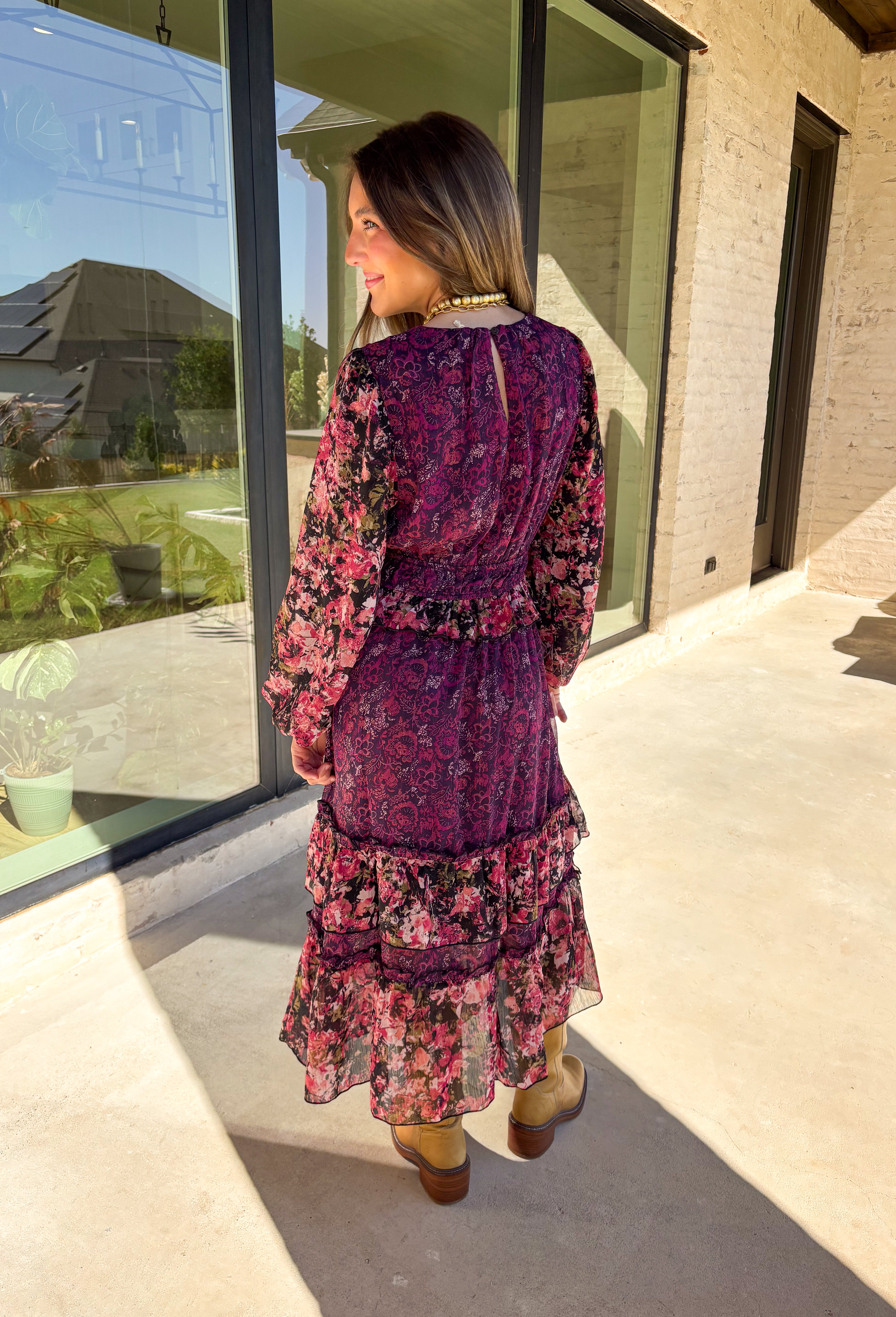 Romantic and striking, this midi dress by Mystree is full of seasonal charm. Crafted in a rich dark purple with a monochromatic floral print, it’s accented by black sleeves featuring a pink floral pattern for a chic contrast. The same floral design is carried through with delicate ruffle detailing, while subtle gold shimmer threading adds a touch of elegance. Finished with an elastic waist and sleeves for comfort, plus a full lining, this dress is as wearable as it is eye-catching.