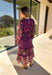 Romantic and striking, this midi dress by Mystree is full of seasonal charm. Crafted in a rich dark purple with a monochromatic floral print, it’s accented by black sleeves featuring a pink floral pattern for a chic contrast. The same floral design is carried through with delicate ruffle detailing, while subtle gold shimmer threading adds a touch of elegance. Finished with an elastic waist and sleeves for comfort, plus a full lining, this dress is as wearable as it is eye-catching.