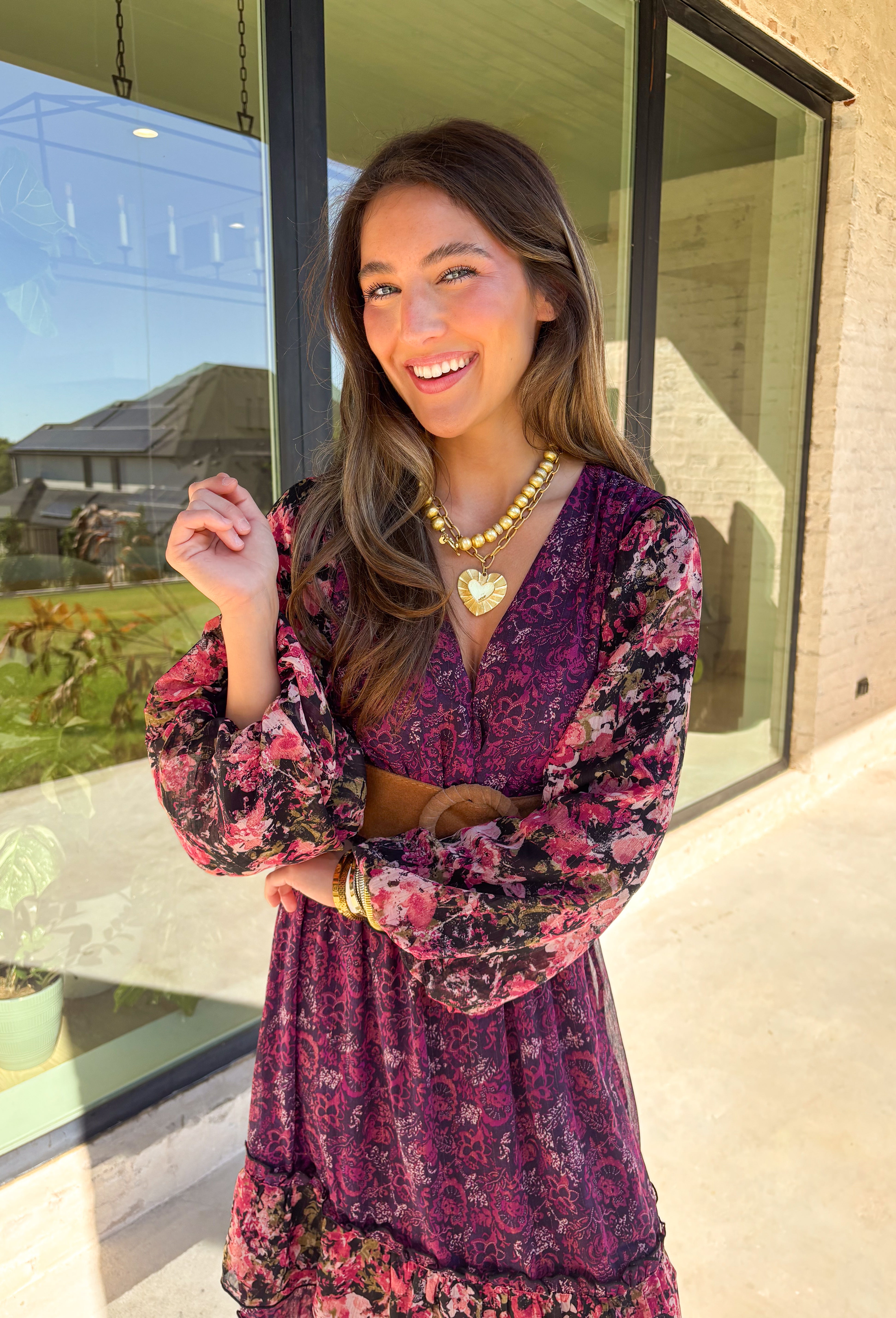 Romantic and striking, this midi dress by Mystree is full of seasonal charm. Crafted in a rich dark purple with a monochromatic floral print, it’s accented by black sleeves featuring a pink floral pattern for a chic contrast. The same floral design is carried through with delicate ruffle detailing, while subtle gold shimmer threading adds a touch of elegance. Finished with an elastic waist and sleeves for comfort, plus a full lining, this dress is as wearable as it is eye-catching.