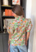 Bright, fresh, and full of spring charm, this white short sleeve top by Entro is the perfect way to add a little color to your everyday look. The colorful floral print features happy pops of orange, green, and pink, while the subtle ruffle neckline keeps it sweet and feminine. Finished with pleated sleeve details and elastic cuffs, it has that “cute but still comfy” vibe we all love.