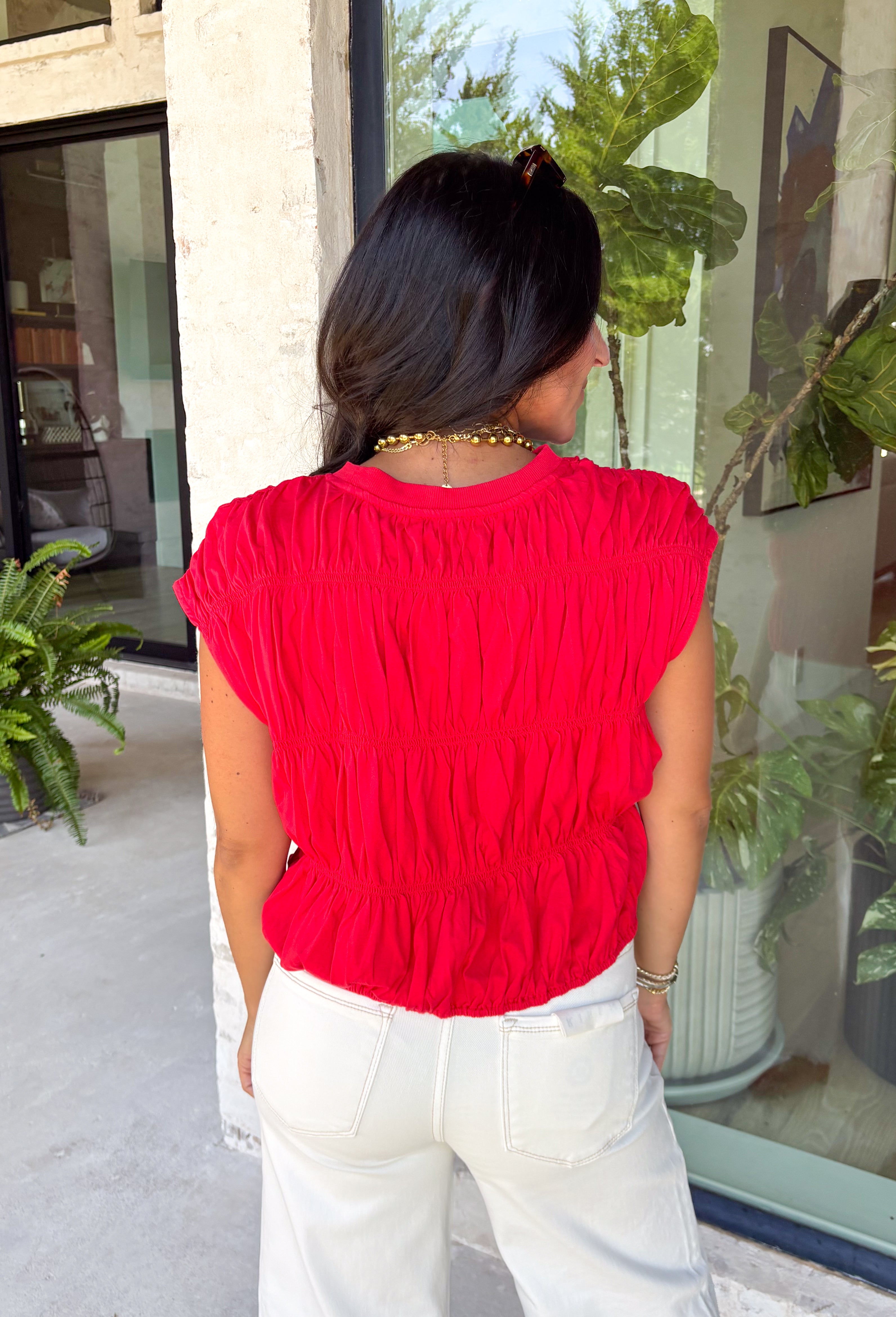 Say hello to your new fall favorite! This rich red short sleeve top brings all the cozy seasonal charm with its tiered peplum silhouette and delicate shirred detailing throughout. The lightweight, textured cotton makes it comfortable enough for those warmer autumn afternoons, while the cropped length and elastic hem create a flattering shape that pairs perfectly with your favorite high-rise denim. 