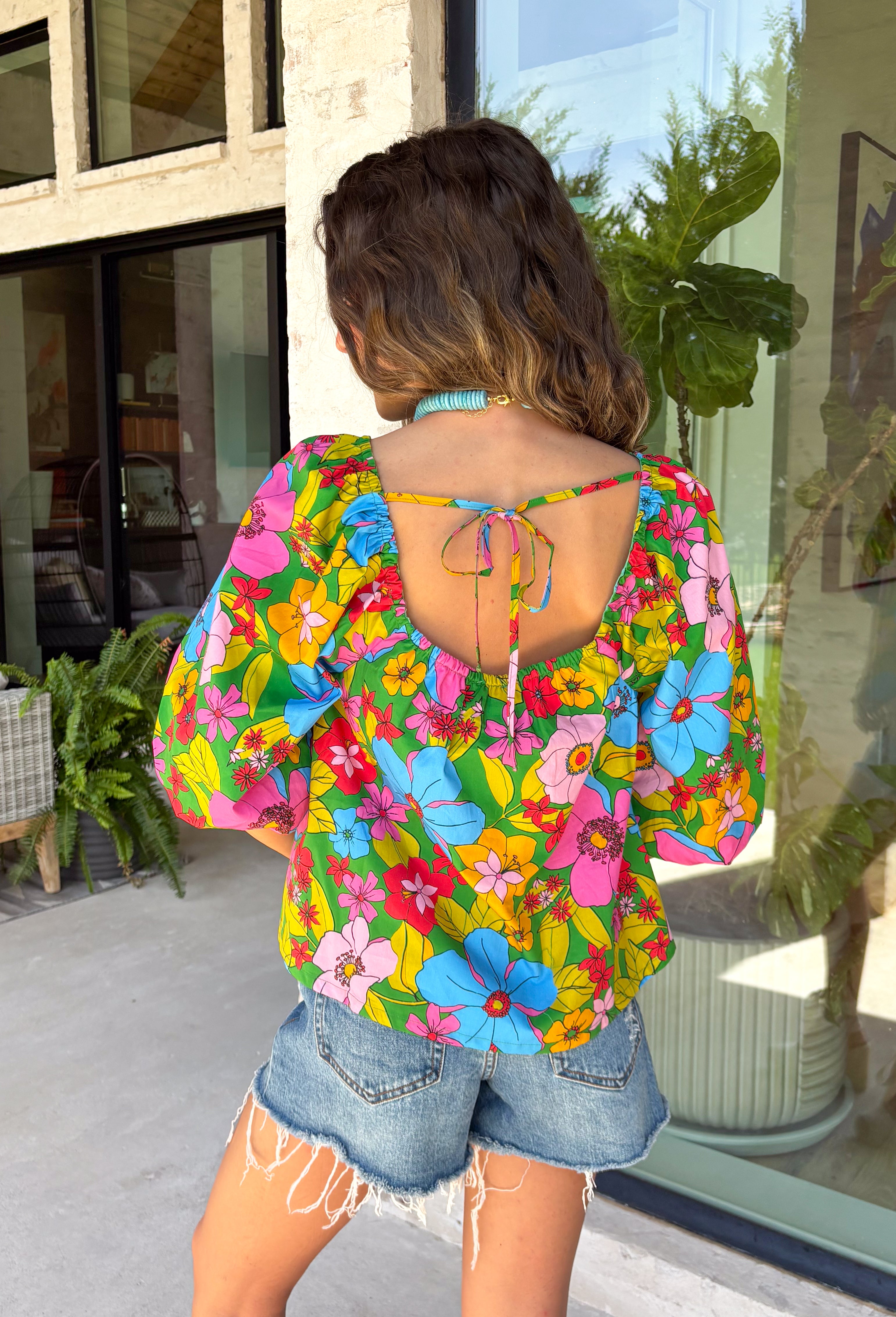 This green floral top is bursting with color and made for sunny summer days! Featuring a vibrant floral print in shades of pink, red, yellow, and blue, it instantly brightens up any outfit. The square neckline gives it a flattering, feminine feel, while the puff sleeves add just the right amount of charm. Finished with a sweet tie detail in the back, this lightweight cotton top is perfect for everything from brunch dates to weekend getaways. 