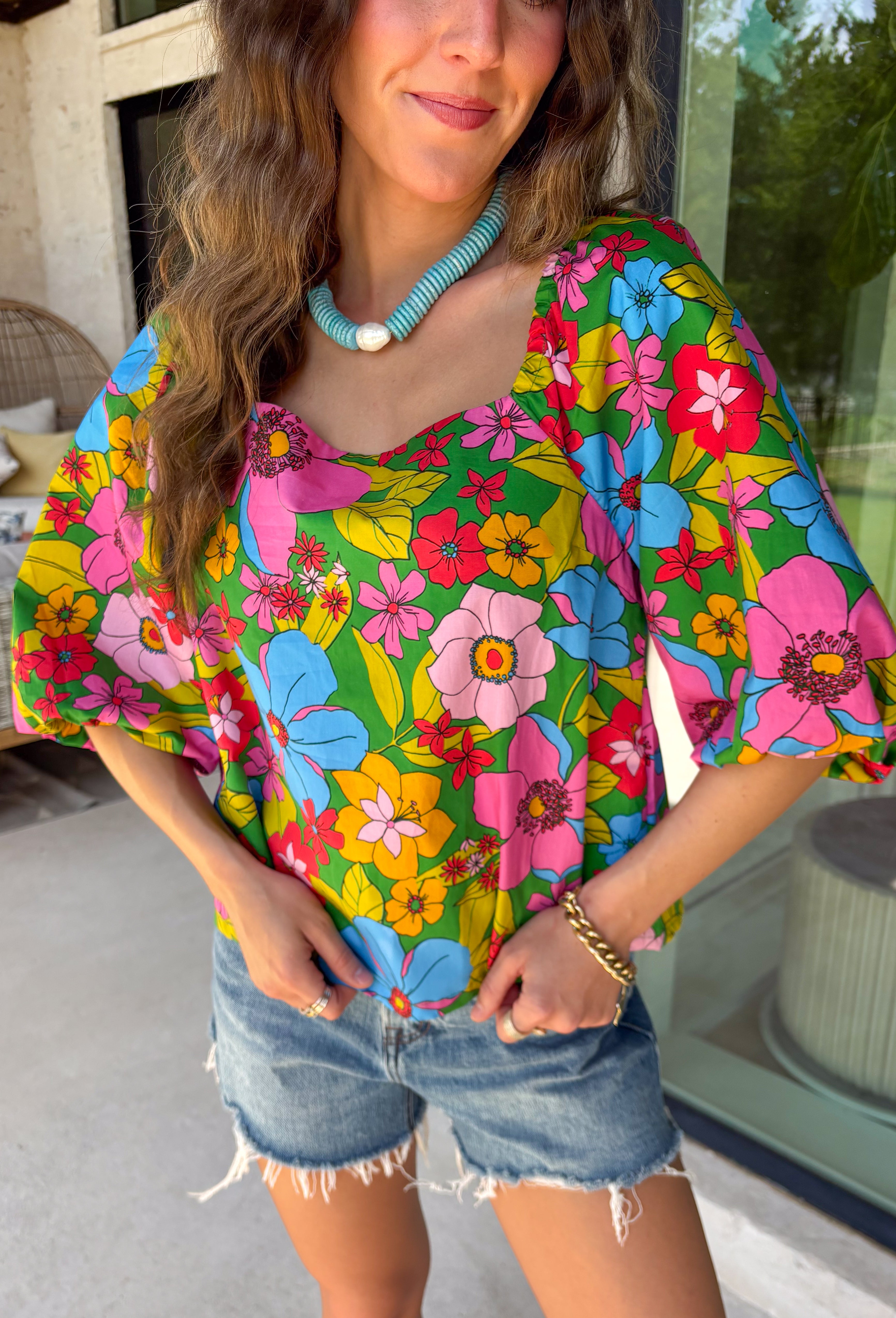 This green floral top is bursting with color and made for sunny summer days! Featuring a vibrant floral print in shades of pink, red, yellow, and blue, it instantly brightens up any outfit. The square neckline gives it a flattering, feminine feel, while the puff sleeves add just the right amount of charm. Finished with a sweet tie detail in the back, this lightweight cotton top is perfect for everything from brunch dates to weekend getaways. 