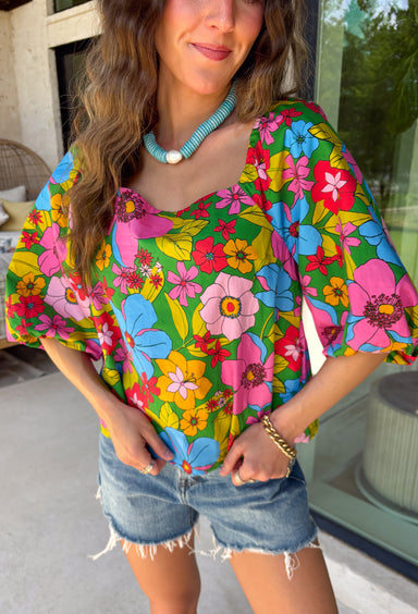 This green floral top is bursting with color and made for sunny summer days! Featuring a vibrant floral print in shades of pink, red, yellow, and blue, it instantly brightens up any outfit. The square neckline gives it a flattering, feminine feel, while the puff sleeves add just the right amount of charm. Finished with a sweet tie detail in the back, this lightweight cotton top is perfect for everything from brunch dates to weekend getaways. 