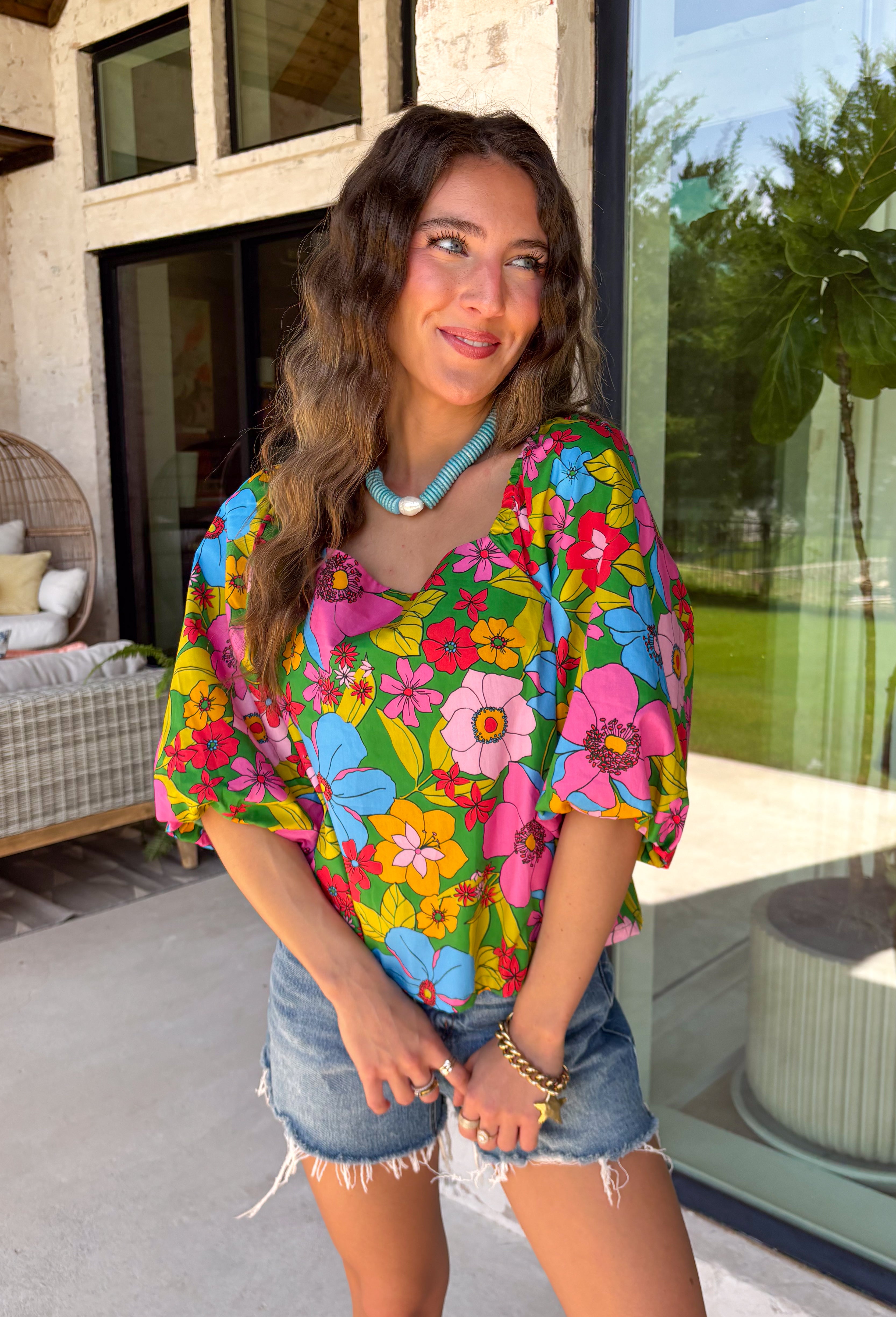 This green floral top is bursting with color and made for sunny summer days! Featuring a vibrant floral print in shades of pink, red, yellow, and blue, it instantly brightens up any outfit. The square neckline gives it a flattering, feminine feel, while the puff sleeves add just the right amount of charm. Finished with a sweet tie detail in the back, this lightweight cotton top is perfect for everything from brunch dates to weekend getaways. 