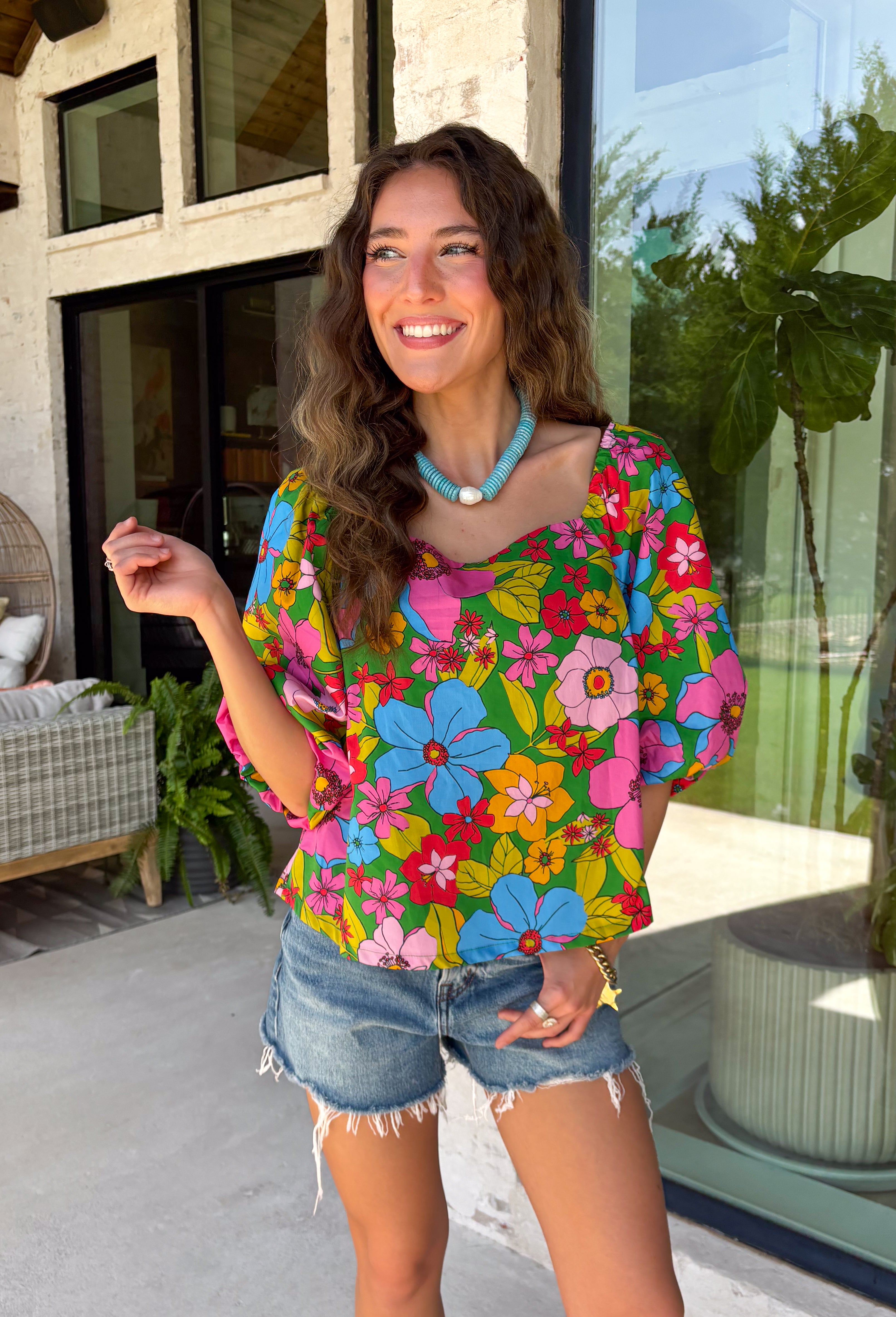 This green floral top is bursting with color and made for sunny summer days! Featuring a vibrant floral print in shades of pink, red, yellow, and blue, it instantly brightens up any outfit. The square neckline gives it a flattering, feminine feel, while the puff sleeves add just the right amount of charm. Finished with a sweet tie detail in the back, this lightweight cotton top is perfect for everything from brunch dates to weekend getaways. 