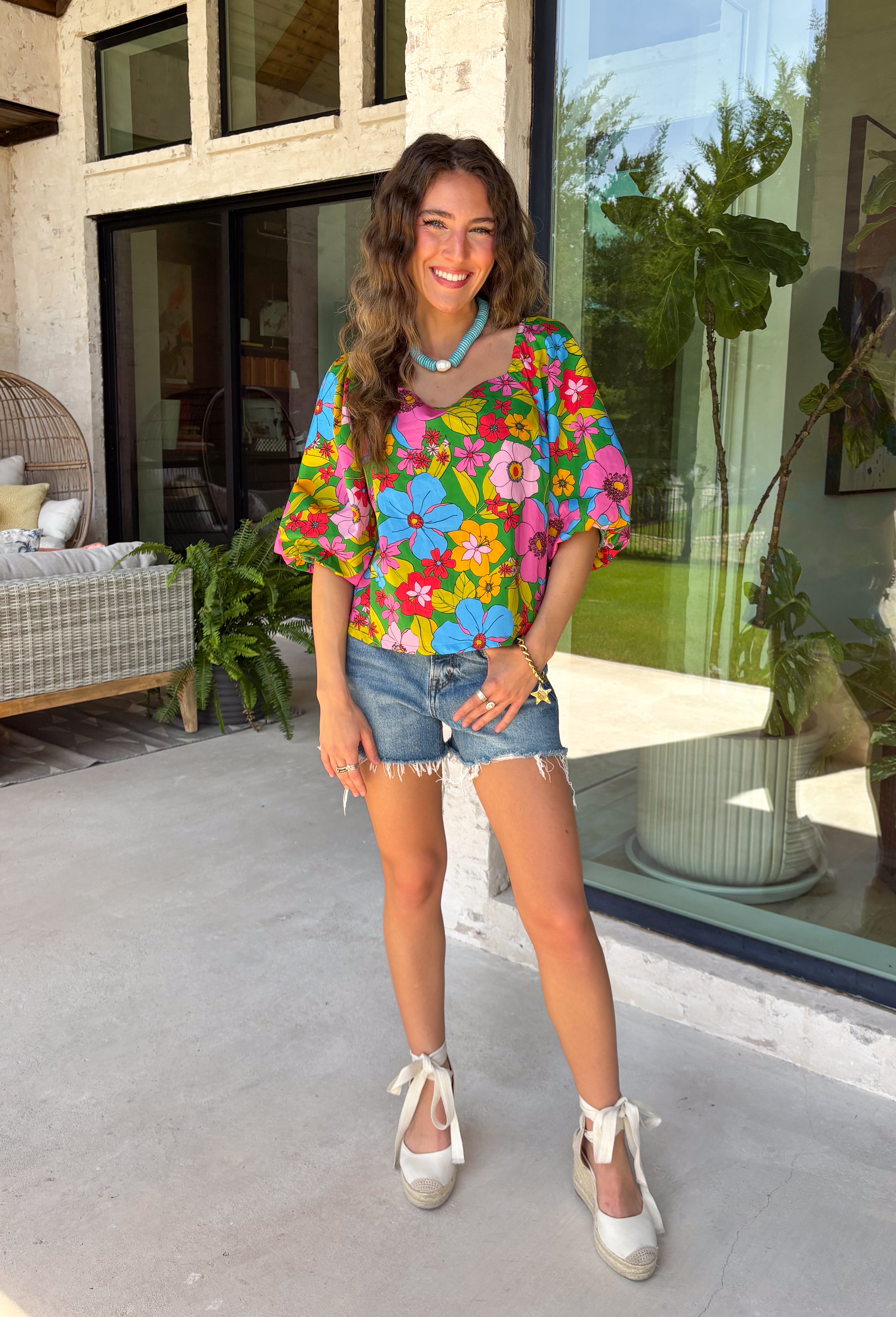 This green floral top is bursting with color and made for sunny summer days! Featuring a vibrant floral print in shades of pink, red, yellow, and blue, it instantly brightens up any outfit. The square neckline gives it a flattering, feminine feel, while the puff sleeves add just the right amount of charm. Finished with a sweet tie detail in the back, this lightweight cotton top is perfect for everything from brunch dates to weekend getaways. 