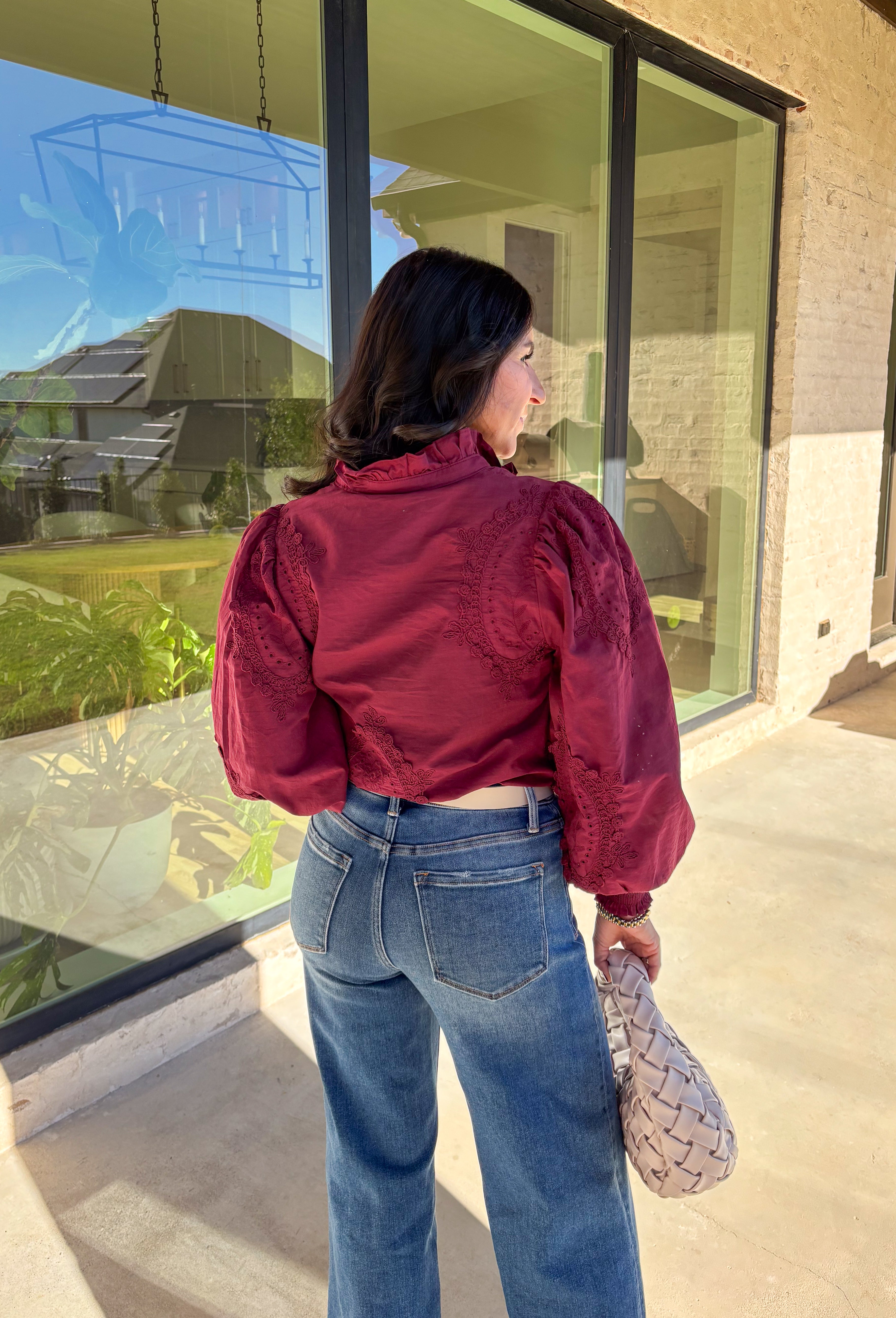 Timeless and full of detail, this burgundy top by Entro adds a refined touch to your fall wardrobe. Featuring an oval embroidered appliqué with eyelet accents, it’s beautifully designed to bring texture and depth to your look. The ruffled stand collar and smocked sleeve cuffs create a feminine finish, while the button-front closure keeps it classic and easy to style. Made from soft cotton, this top blends comfort and elegance effortlessly.