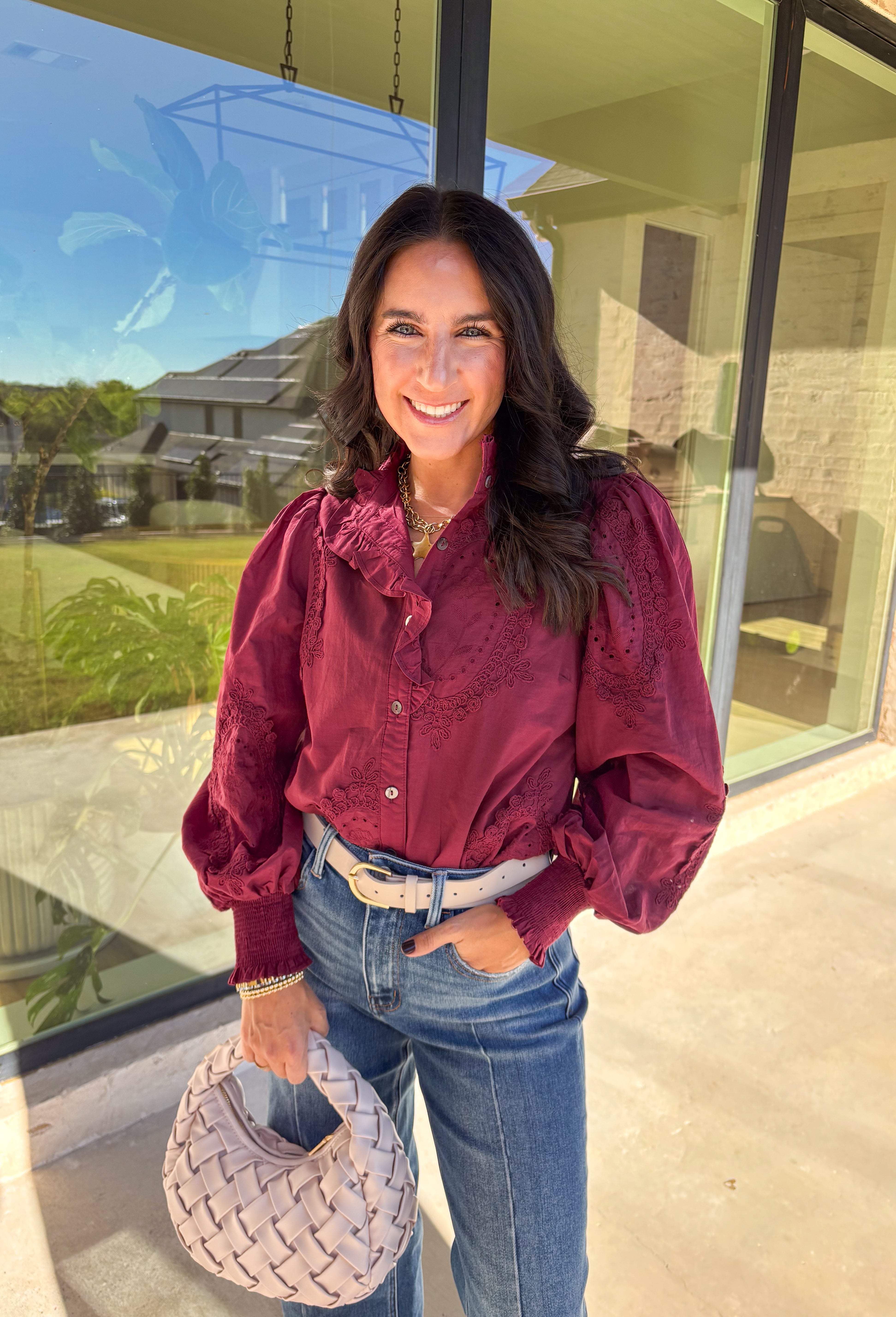 Timeless and full of detail, this burgundy top by Entro adds a refined touch to your fall wardrobe. Featuring an oval embroidered appliqué with eyelet accents, it’s beautifully designed to bring texture and depth to your look. The ruffled stand collar and smocked sleeve cuffs create a feminine finish, while the button-front closure keeps it classic and easy to style. Made from soft cotton, this top blends comfort and elegance effortlessly.