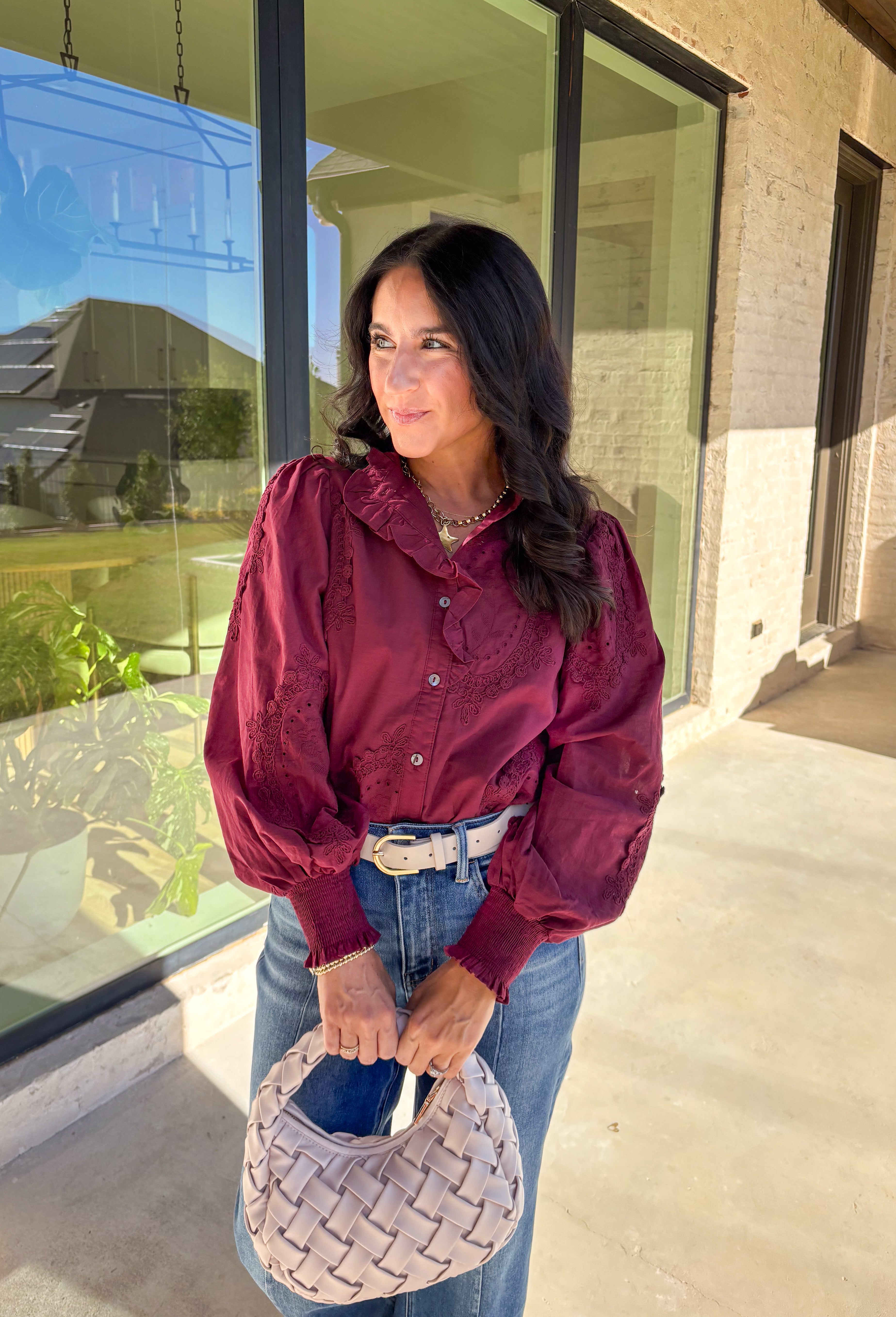 Timeless and full of detail, this burgundy top by Entro adds a refined touch to your fall wardrobe. Featuring an oval embroidered appliqué with eyelet accents, it’s beautifully designed to bring texture and depth to your look. The ruffled stand collar and smocked sleeve cuffs create a feminine finish, while the button-front closure keeps it classic and easy to style. Made from soft cotton, this top blends comfort and elegance effortlessly.