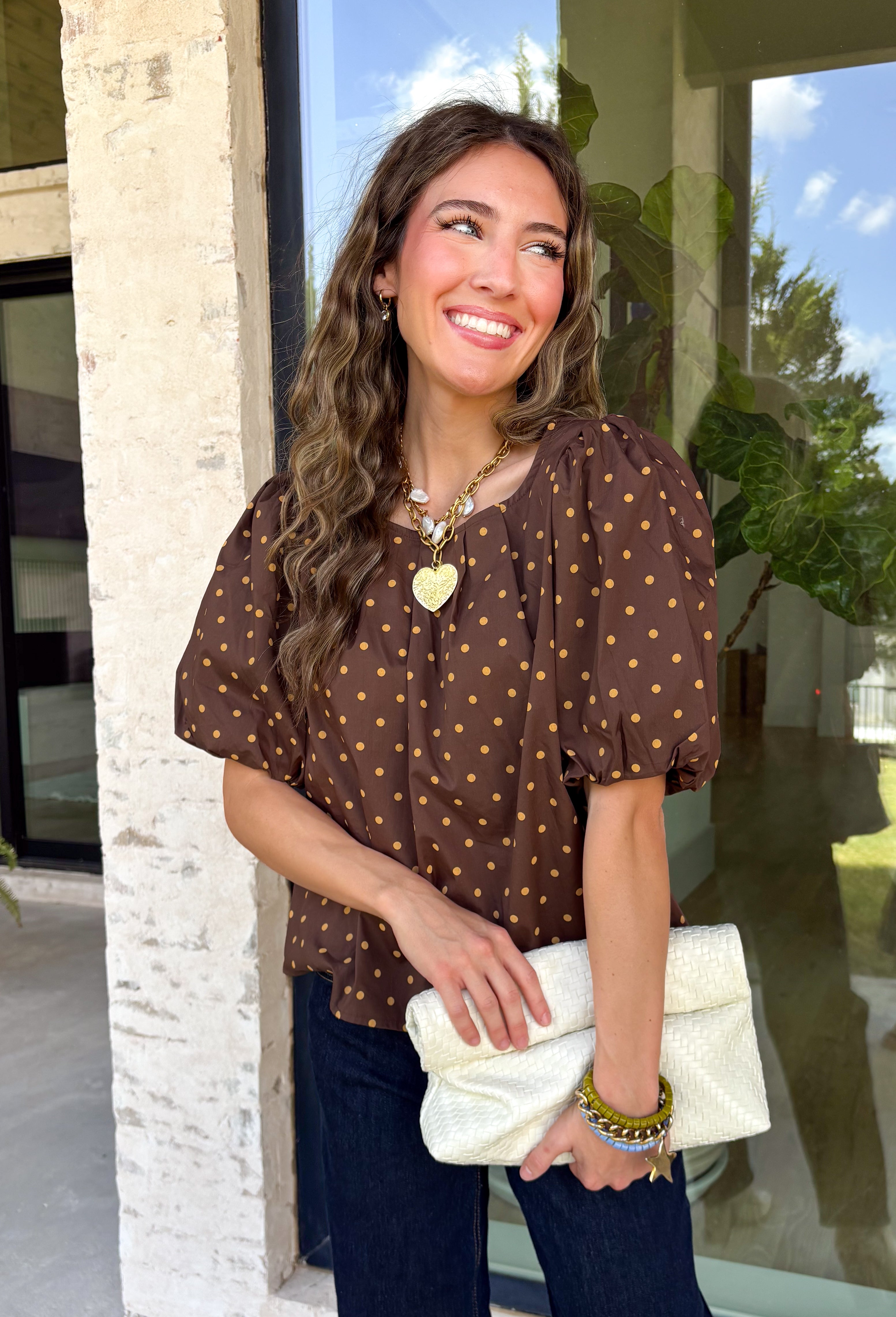 Classic polka dots never go out of style, and this charming top from Day + Moon is the perfect addition to your fall wardrobe. Designed in a rich brown hue with a timeless tan polka dot print, this effortlessly feminine blouse is easy to dress up or down. The puff sleeves add a soft, romantic touch, while the keyhole button closure at the back creates a polished finishing detail. Crafted from breathable cotton, this versatile top is perfect for everything from workdays to weekend outings.