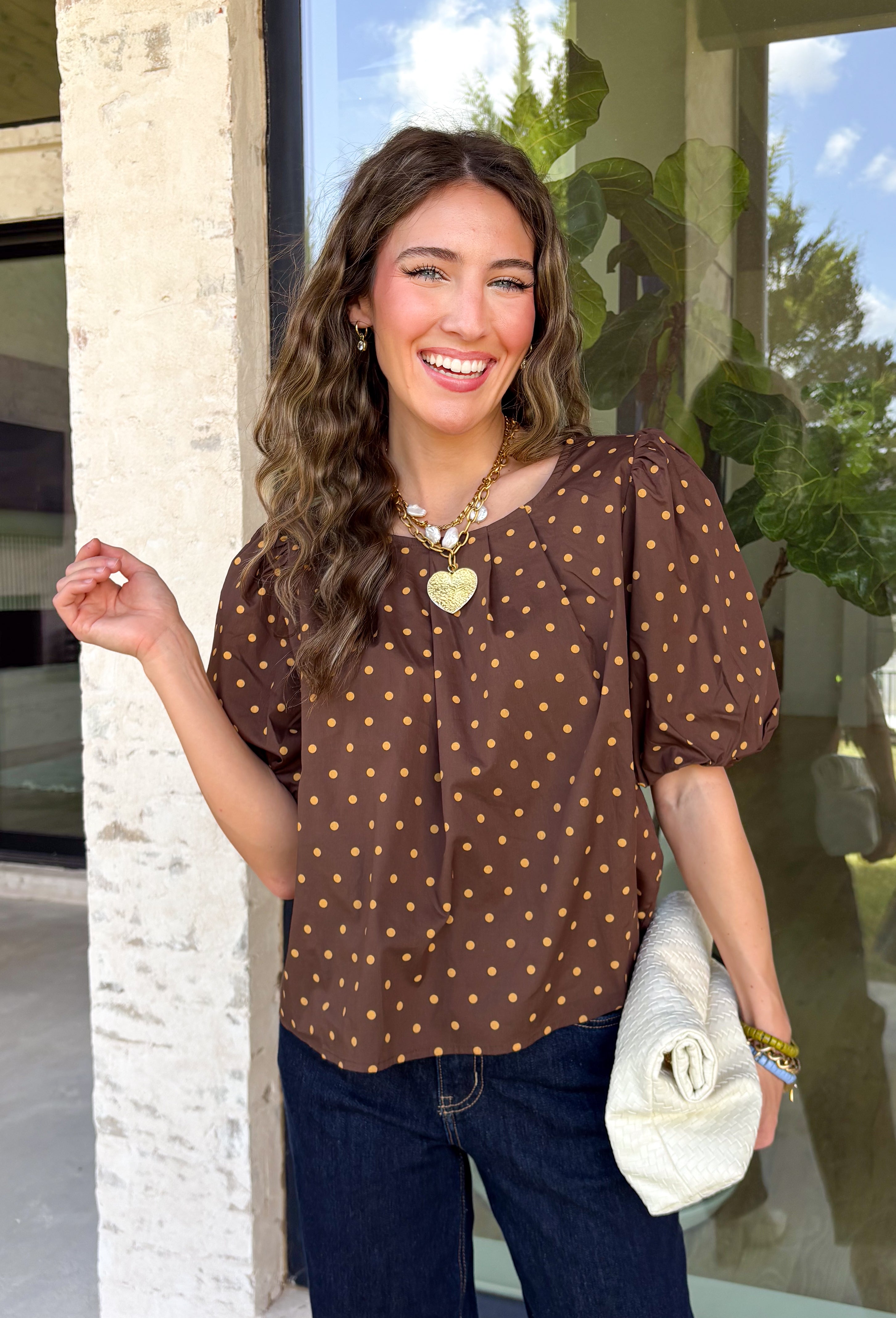 Classic polka dots never go out of style, and this charming top from Day + Moon is the perfect addition to your fall wardrobe. Designed in a rich brown hue with a timeless tan polka dot print, this effortlessly feminine blouse is easy to dress up or down. The puff sleeves add a soft, romantic touch, while the keyhole button closure at the back creates a polished finishing detail. Crafted from breathable cotton, this versatile top is perfect for everything from workdays to weekend outings.