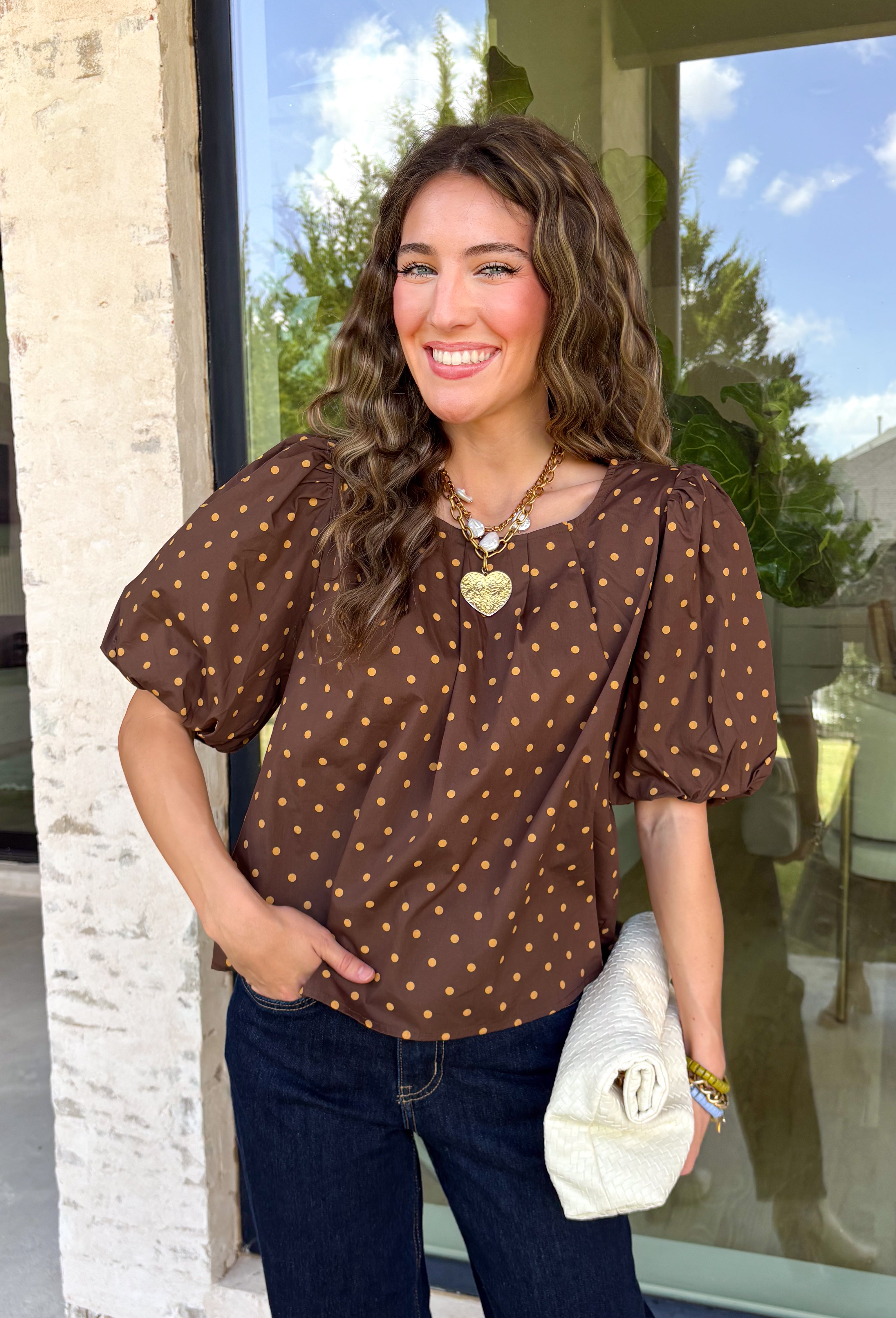 Classic polka dots never go out of style, and this charming top from Day + Moon is the perfect addition to your fall wardrobe. Designed in a rich brown hue with a timeless tan polka dot print, this effortlessly feminine blouse is easy to dress up or down. The puff sleeves add a soft, romantic touch, while the keyhole button closure at the back creates a polished finishing detail. Crafted from breathable cotton, this versatile top is perfect for everything from workdays to weekend outings.