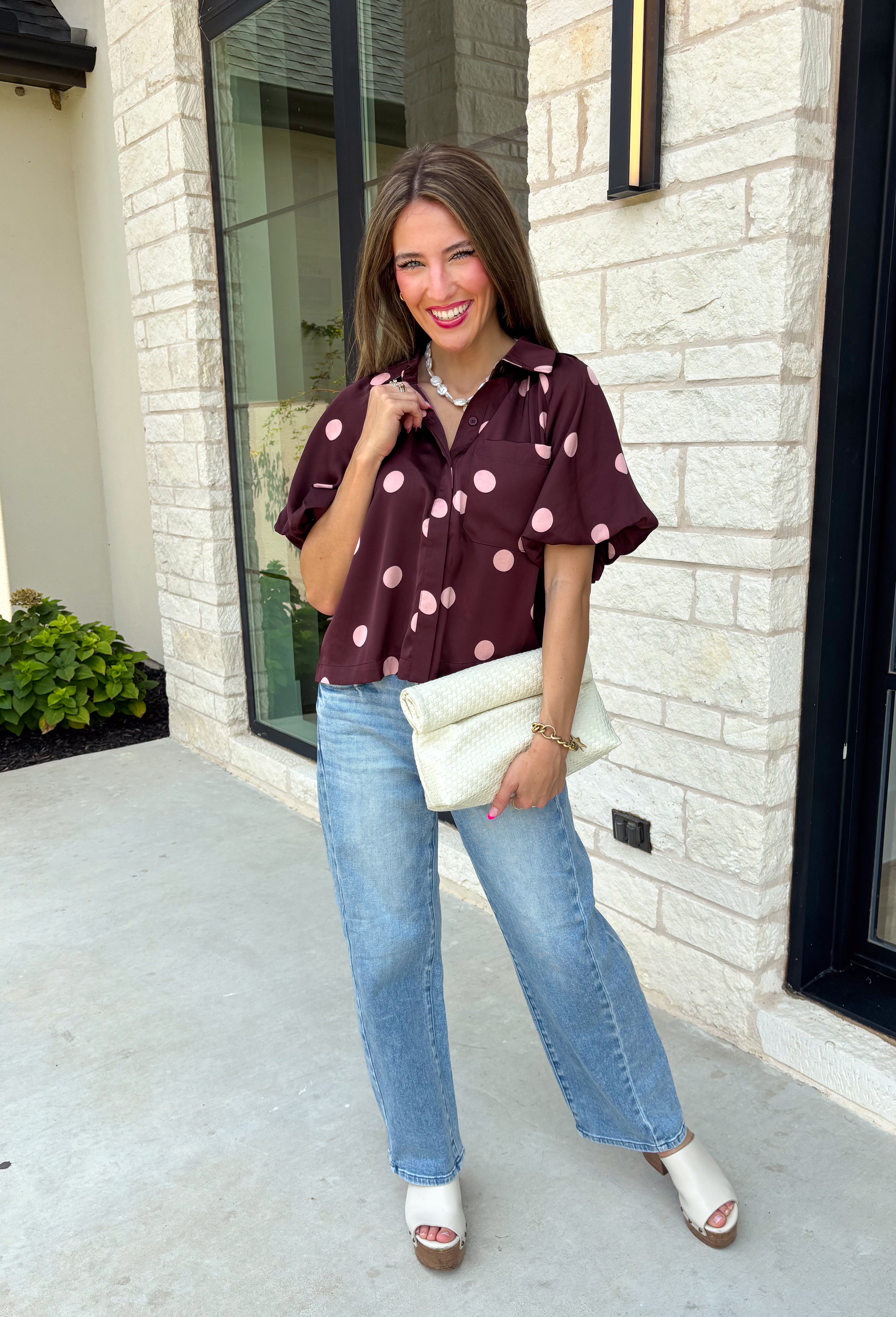 Classic polka dots meet rich fall color in this charming burgundy top! Featuring a soft mauve polka dot print, this top is an effortless way to add personality to your everyday wardrobe. The hidden button front creates a clean, polished look, while the foldover neckline and front pocket add timeless details you'll love. Finished with short puff sleeves, this versatile top is perfect for everything from workdays to weekend brunches and pairs beautifully with your favorite fall denim.