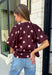 Classic polka dots meet rich fall color in this charming burgundy top! Featuring a soft mauve polka dot print, this top is an effortless way to add personality to your everyday wardrobe. The hidden button front creates a clean, polished look, while the foldover neckline and front pocket add timeless details you'll love. Finished with short puff sleeves, this versatile top is perfect for everything from workdays to weekend brunches and pairs beautifully with your favorite fall denim.