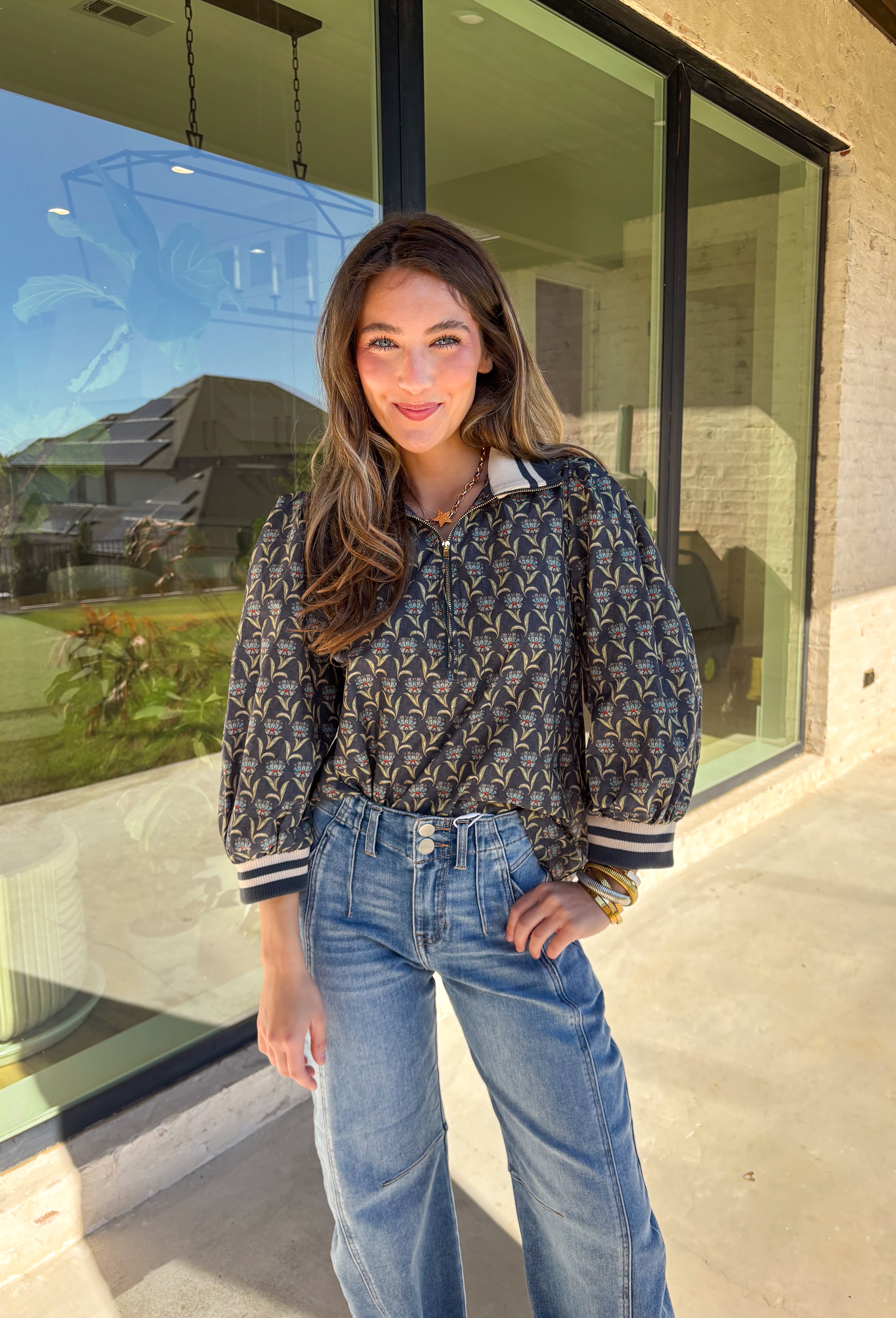 This midnight floral top by Entro is the perfect blend of casual comfort and standout style. Featuring ¾ puff sleeves and a sporty contrast ribbed stand collar and cuffs, it adds a playful edge to the feminine floral print. Shades of green and blue give it a cool, seasonal vibe, while the half zip front closure adds a touch of versatility. Made from 100% cotton, it’s lightweight, breathable, and perfect for transitional weather.