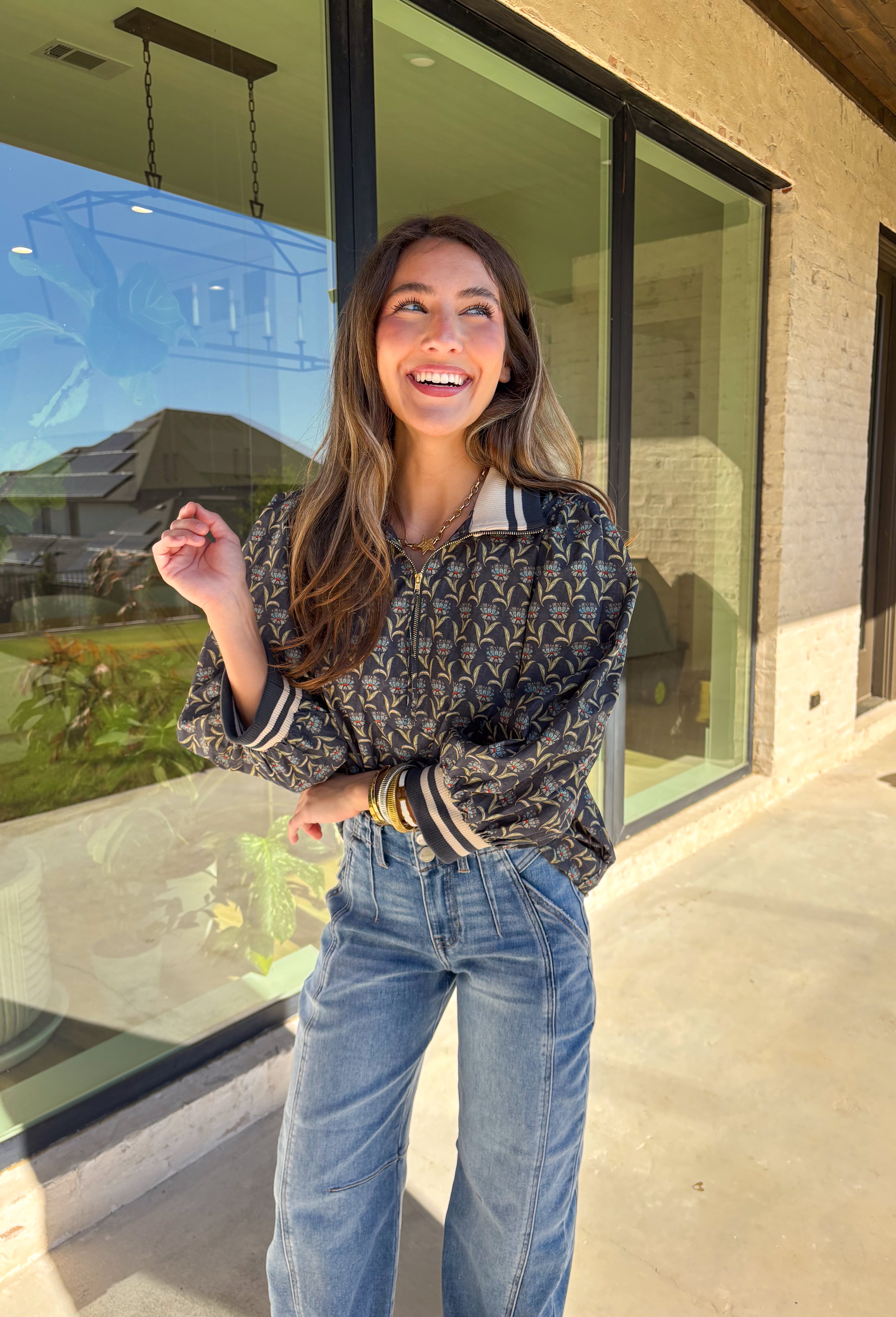 This midnight floral top by Entro is the perfect blend of casual comfort and standout style. Featuring ¾ puff sleeves and a sporty contrast ribbed stand collar and cuffs, it adds a playful edge to the feminine floral print. Shades of green and blue give it a cool, seasonal vibe, while the half zip front closure adds a touch of versatility. Made from 100% cotton, it’s lightweight, breathable, and perfect for transitional weather.