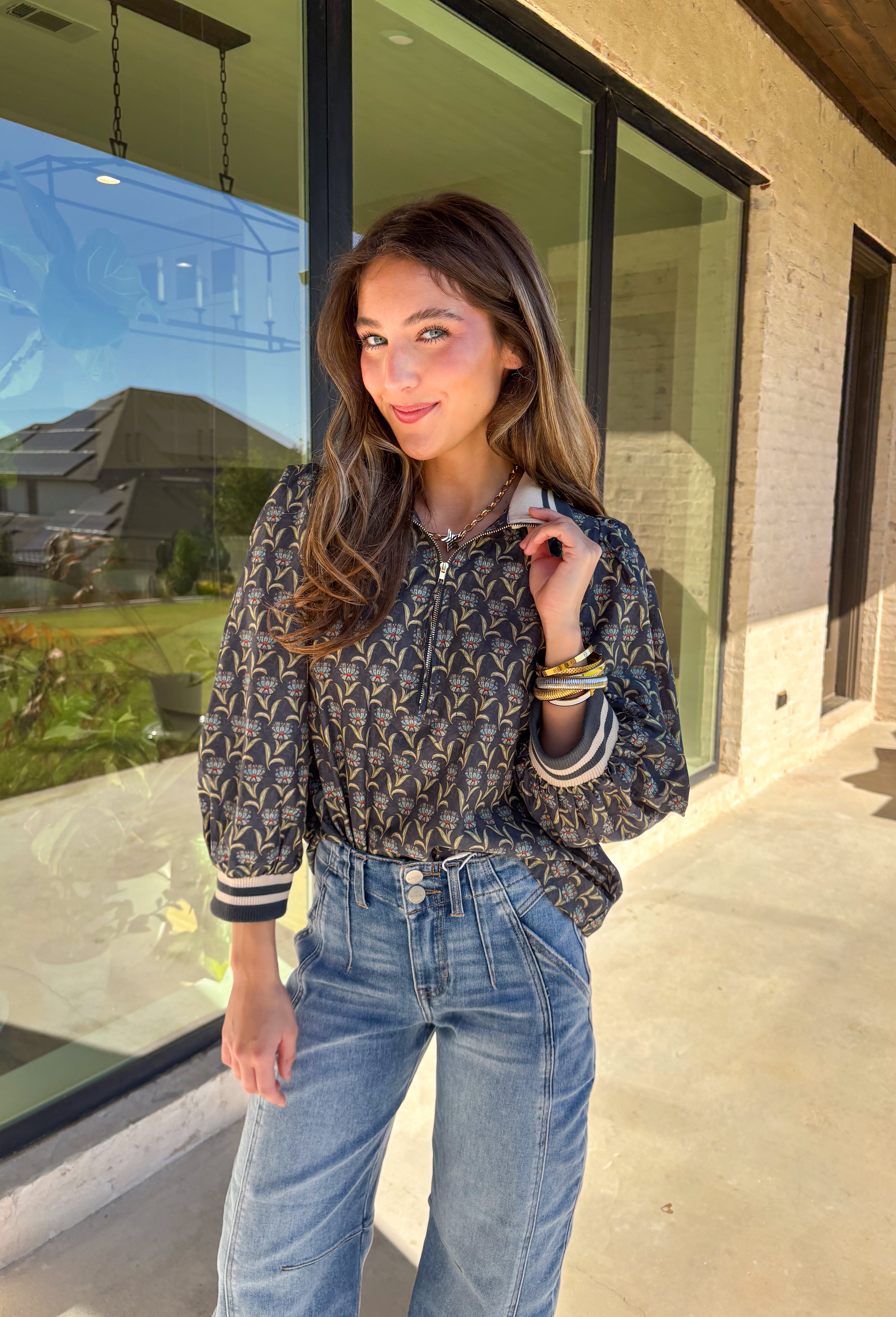 This midnight floral top by Entro is the perfect blend of casual comfort and standout style. Featuring ¾ puff sleeves and a sporty contrast ribbed stand collar and cuffs, it adds a playful edge to the feminine floral print. Shades of green and blue give it a cool, seasonal vibe, while the half zip front closure adds a touch of versatility. Made from 100% cotton, it’s lightweight, breathable, and perfect for transitional weather.