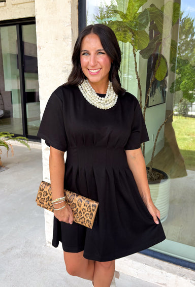 Every wardrobe deserves a little black dress that's as comfortable as it is stylish! This timeless dress is designed with flattering pintuck detailing at the waist to create an effortlessly polished silhouette you'll love. The soft knit fabric offers all-day comfort, while the classic round neckline and side pockets make it an easy choice for everything from workdays to dinner dates and weekend outings. 