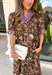Bring vibrant seasonal color to your wardrobe with this beautifully feminine midi dress from Entro. Designed with a rich olive backdrop and a stunning floral print in shades of magenta and white, this timeless dress is perfect for everything from brunch dates to family gatherings. The button-front design and subtle ruffle neckline create a classic, polished look, while the puff sleeves add just the right touch of charm.