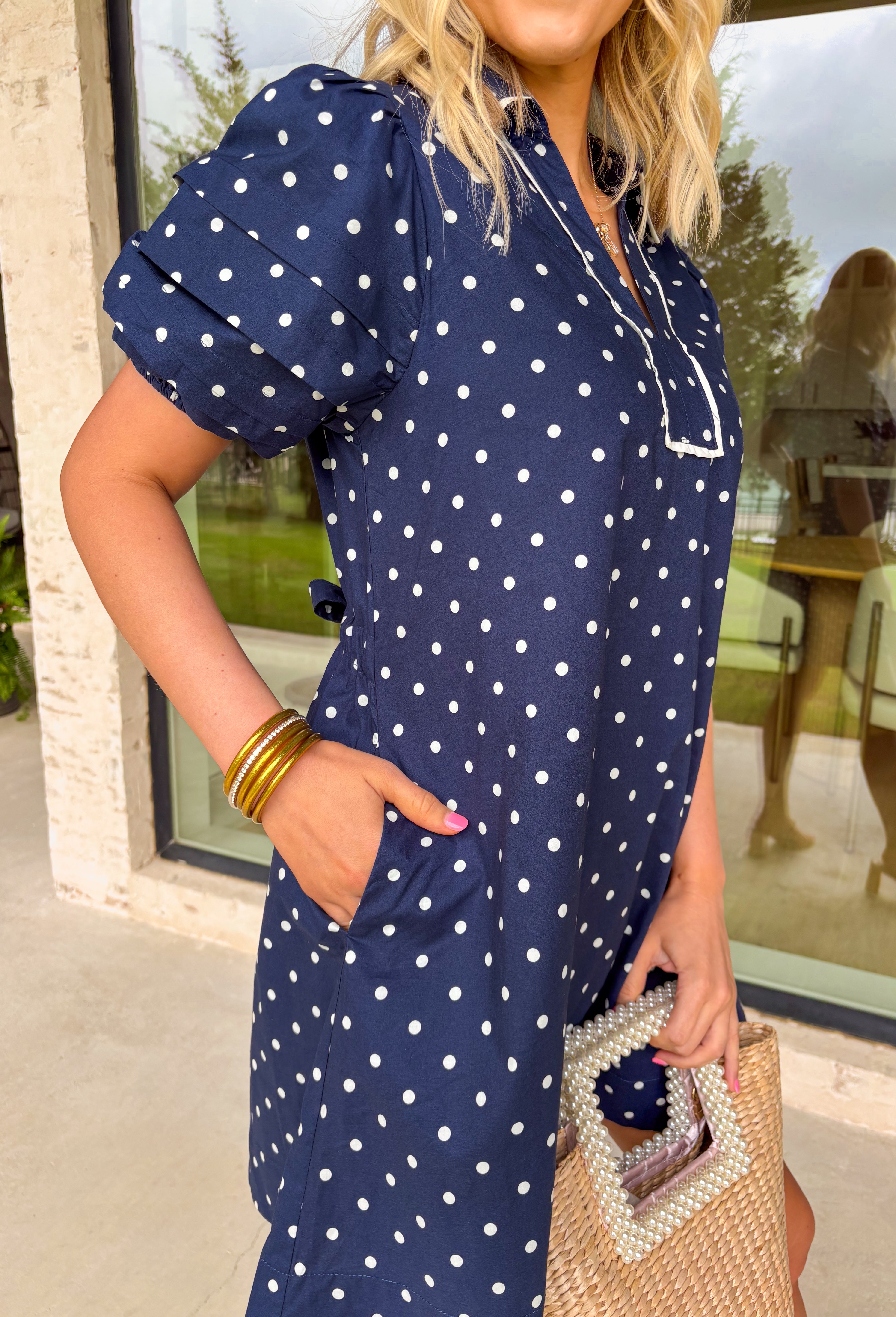 You can never go wrong with classic navy and white polka dots! This dress brings timeless charm with a playful twist. Designed with layered short puff sleeves and elasticated openings, it has just the right amount of volume while staying comfortable and easy to wear. The flattering v-neckline with a collar adds a polished touch, while the elasticated back waist and self-tie detail create a cinched, feminine shape.