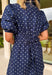 You can never go wrong with classic navy and white polka dots! This dress brings timeless charm with a playful twist. Designed with layered short puff sleeves and elasticated openings, it has just the right amount of volume while staying comfortable and easy to wear. The flattering v-neckline with a collar adds a polished touch, while the elasticated back waist and self-tie detail create a cinched, feminine shape.