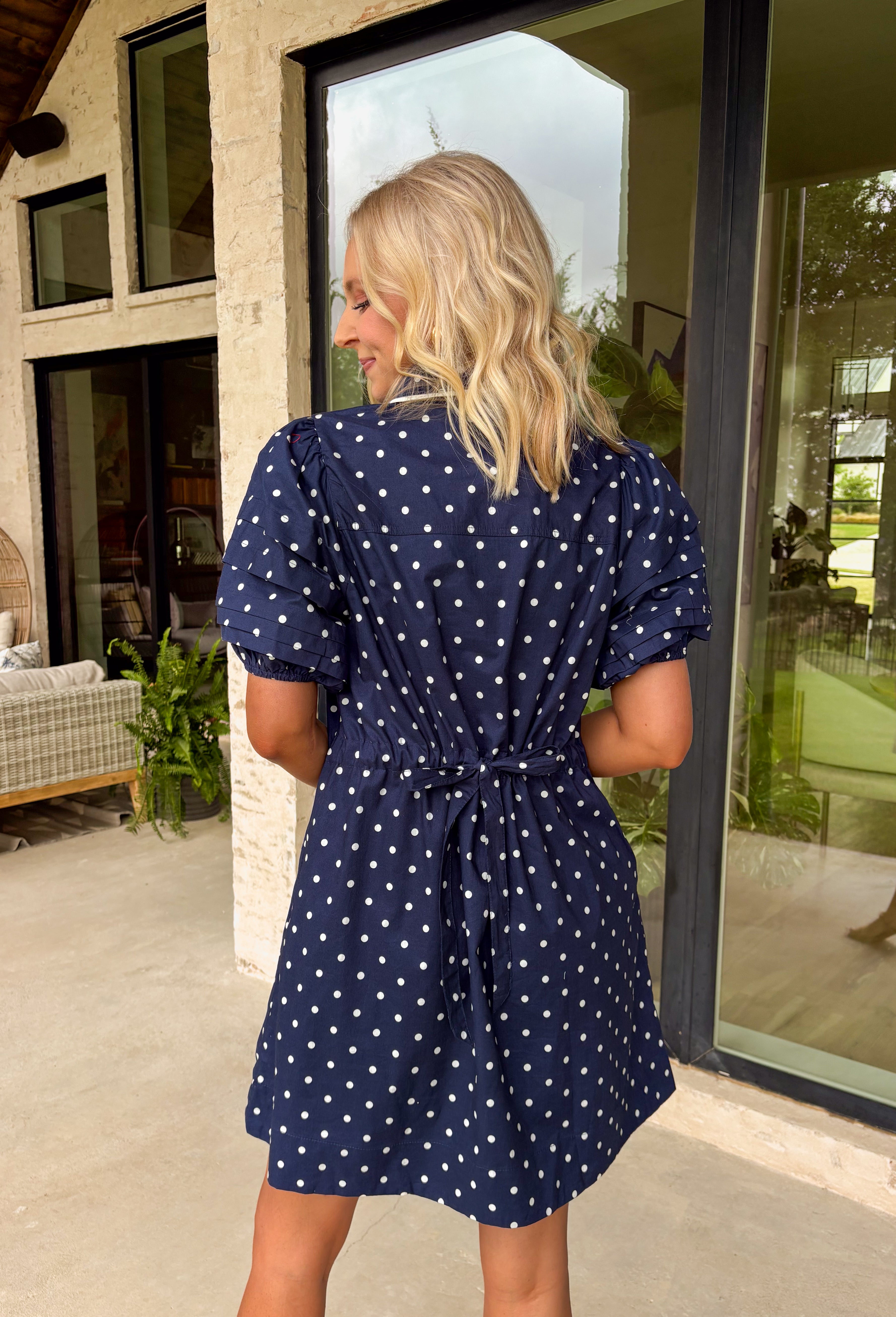 You can never go wrong with classic navy and white polka dots! This dress brings timeless charm with a playful twist. Designed with layered short puff sleeves and elasticated openings, it has just the right amount of volume while staying comfortable and easy to wear. The flattering v-neckline with a collar adds a polished touch, while the elasticated back waist and self-tie detail create a cinched, feminine shape.