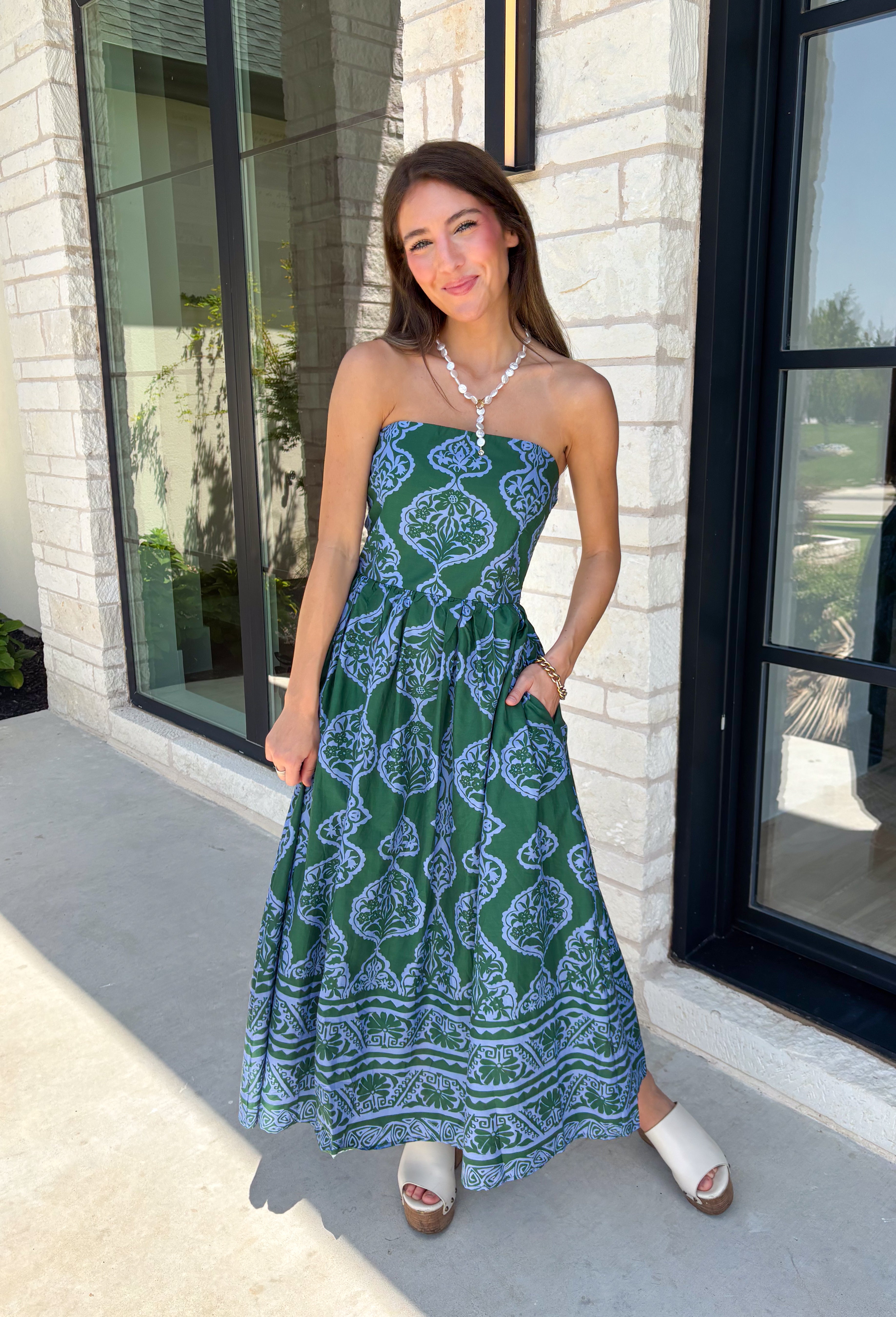 Make a statement this season in this effortlessly beautiful hunter green midi dress! Featuring a light blue abstract print throughout, this strapless silhouette is both timeless and eye-catching. The smocked back bodice offers a comfortable, flattering fit, while the structured zipper closure keeps everything secure. Finished with side pockets and a fully lined design, this cotton midi dress is perfect for fall weddings, dinner dates, and family gatherings.