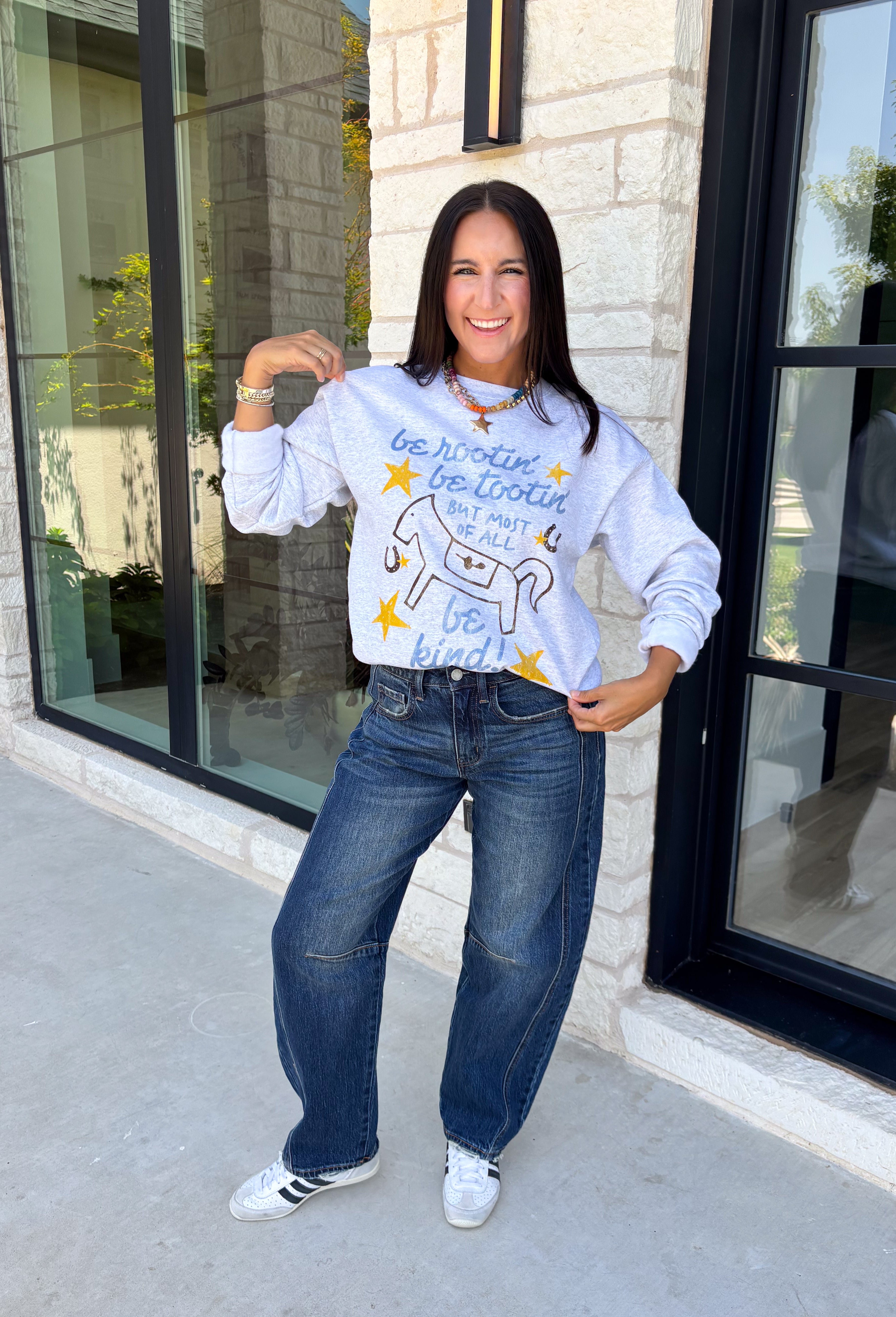 A little western charm and a whole lot of kindness make this sweatshirt an instant favorite! Featuring the playful phrase "Be Rootin', Be Tootin', But Most Of All Be Kind," this heather grey pullover is finished with an abstract illustration of a horse, horseshoe, and stars. The fleece-lined interior keeps you warm and cozy, making it the perfect sweatshirt for everything from weekend errands and football games to bonfires and relaxing at home. 