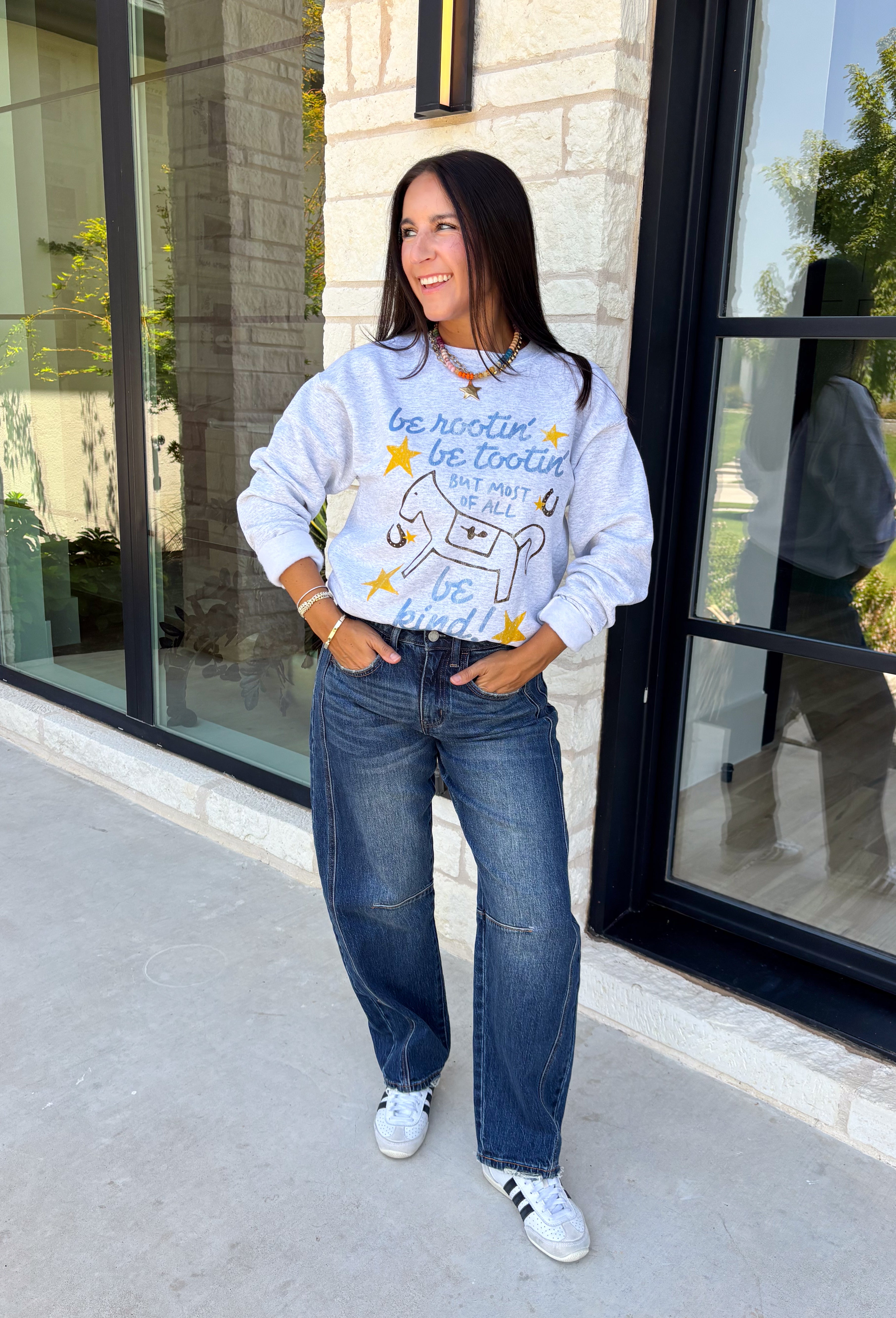 A little western charm and a whole lot of kindness make this sweatshirt an instant favorite! Featuring the playful phrase "Be Rootin', Be Tootin', But Most Of All Be Kind," this heather grey pullover is finished with an abstract illustration of a horse, horseshoe, and stars. The fleece-lined interior keeps you warm and cozy, making it the perfect sweatshirt for everything from weekend errands and football games to bonfires and relaxing at home. 