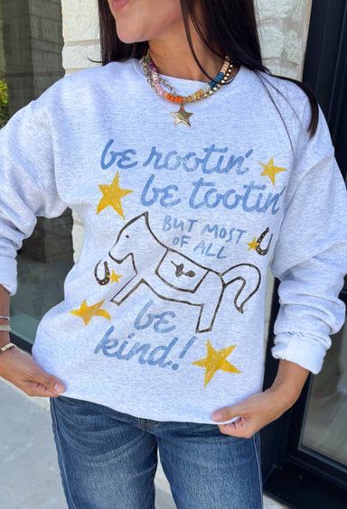 A little western charm and a whole lot of kindness make this sweatshirt an instant favorite! Featuring the playful phrase "Be Rootin', Be Tootin', But Most Of All Be Kind," this heather grey pullover is finished with an abstract illustration of a horse, horseshoe, and stars. The fleece-lined interior keeps you warm and cozy, making it the perfect sweatshirt for everything from weekend errands and football games to bonfires and relaxing at home. 