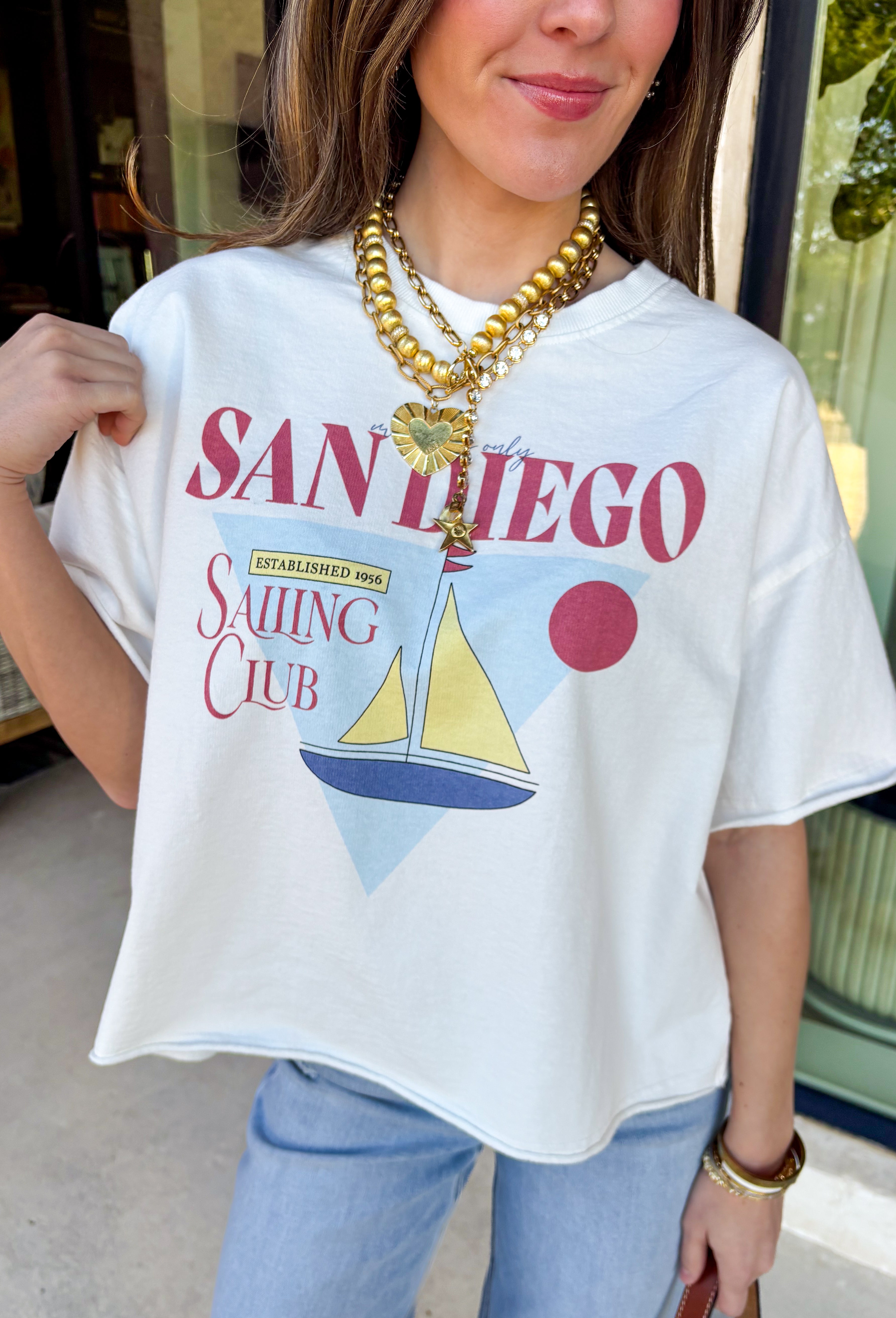 Bring on the sunshine vibes! This white short sleeve graphic tee by Wishlist has the cutest vintage coastal feel with its “Members Only San Diego Sailing Club Established 1956” design. Featuring a retro sailboat graphic and little sun drawing in shades of blue, butter yellow, and brick, it feels like something you found at the coolest beach-town shop. Soft, breathable cotton makes it an easy everyday staple—perfect for spring weekends, travel days, and casual days when you still want to look cute.